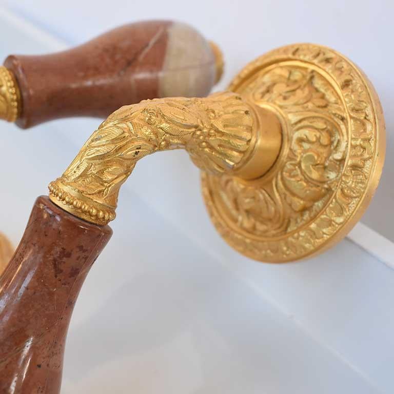 Beautiful set of Sherle Wagner gold plated door levers in brown onyx. This pair features gold plated floral and botanical details and a brown pink onyx marble handle. A gorgeous detail for any passageway.

Measures: Each handle is approximately