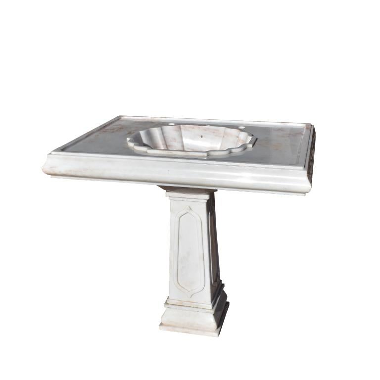 Vintage Sherle Wagner Rose Aurora Marble pedestal sink. The marble on this beautiful piece has been cut from a single block of stone and features soft pink veining against a lovely white stone. 

A large rectangular top fits snugly on a square