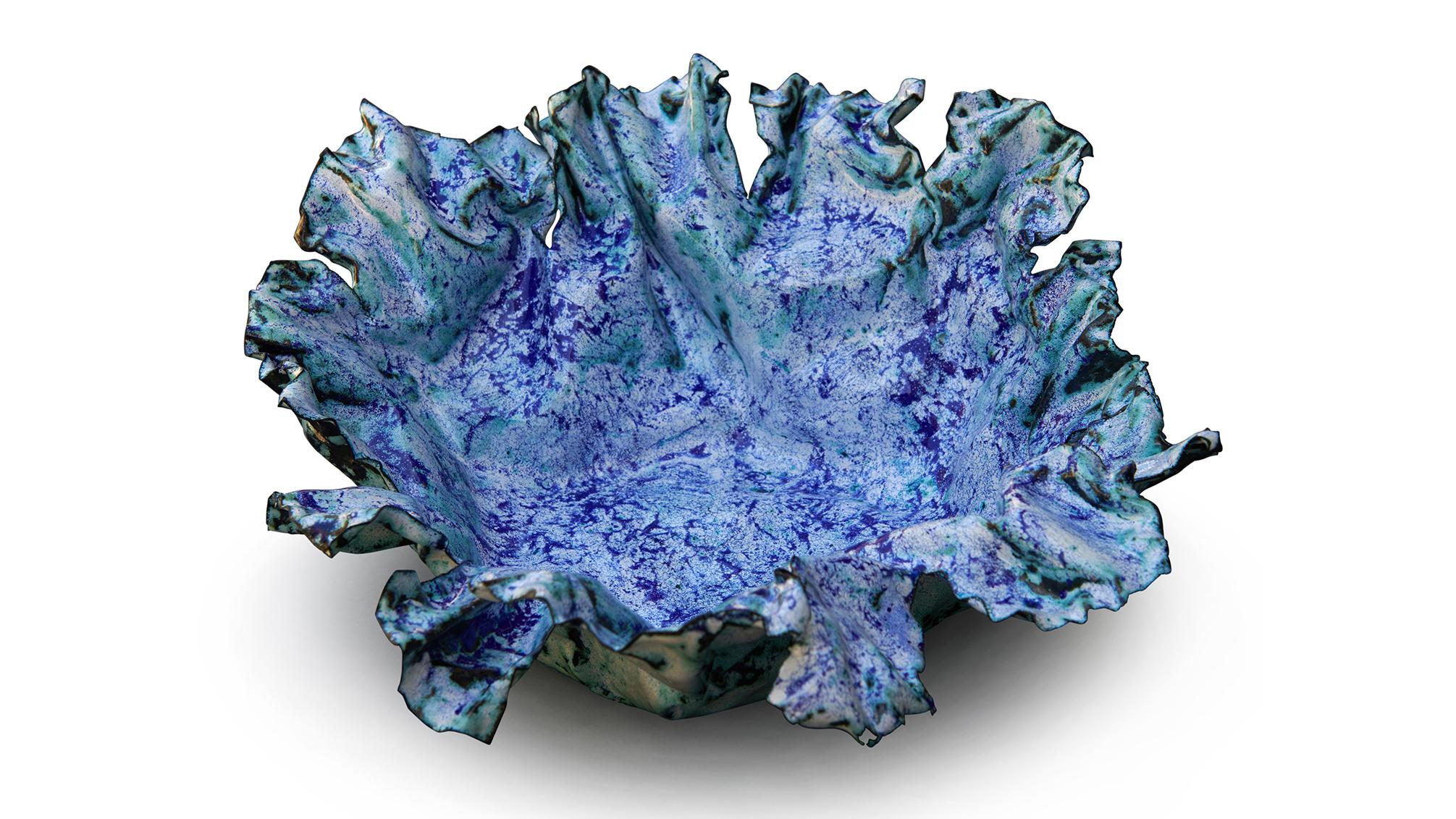 This custom shaped bowl has an organic flow with edges that have been carefully sculpted to add a visual interest to the shape. The blue color has been gently dappled on to a white layer, creating many hues of blues.