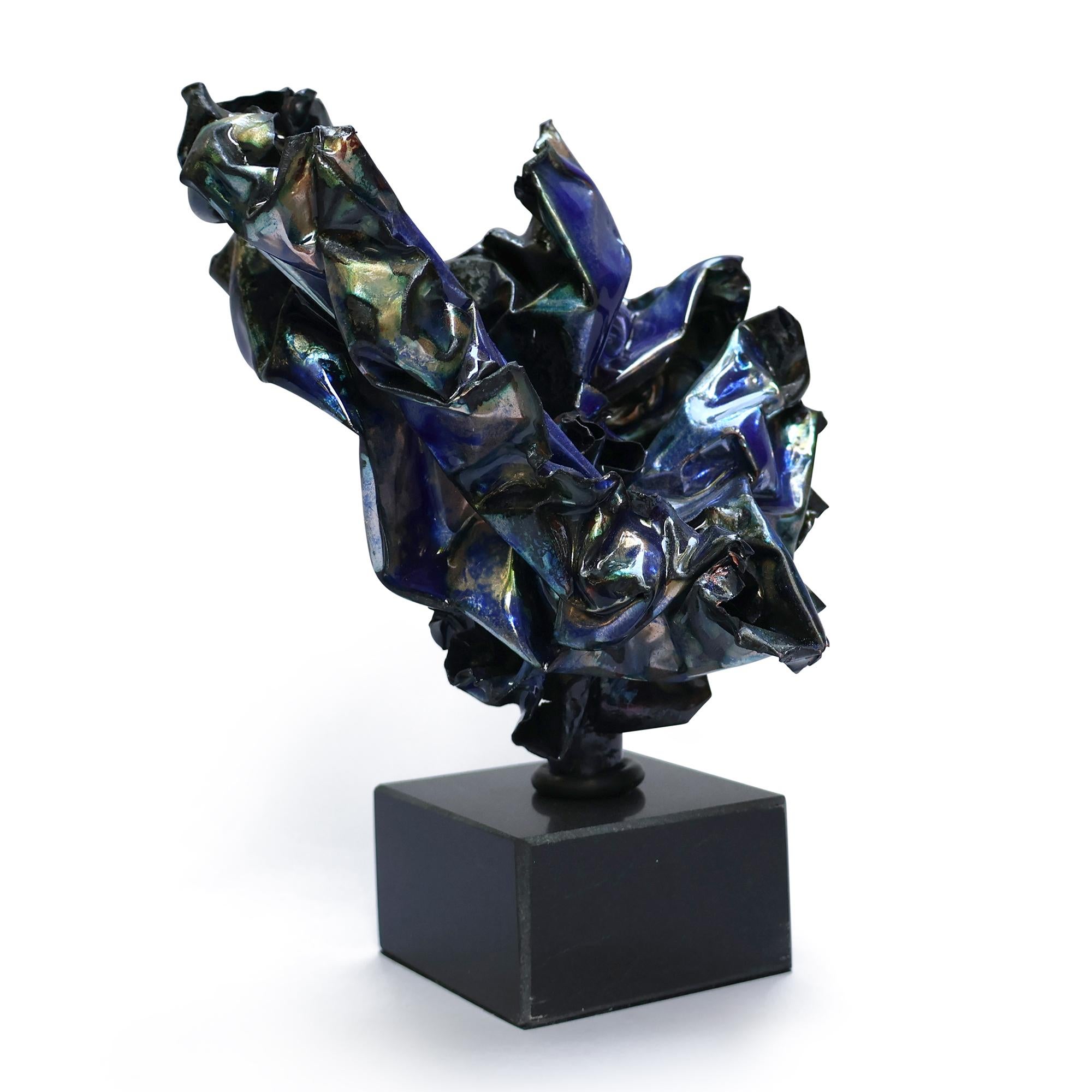 This sculpture features rich blue hues blending with greens and copper, creating a visually captivating abstract artwork.  The enamel finish gives it a liquid-like luminescence.   There is a base layer of soft glass that separates during the firing