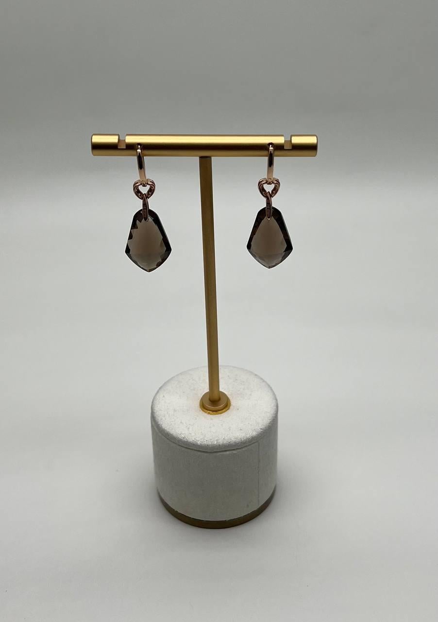 A sophisticated pair of earrings, featuring a sleek design with dark, faceted brown Smoky Quartz suspended from delicate, rose gold loops. 14K Yellow Gold. 0.25 CTW Diamonds. 14.15 CTW Brown Smoky Quartz.