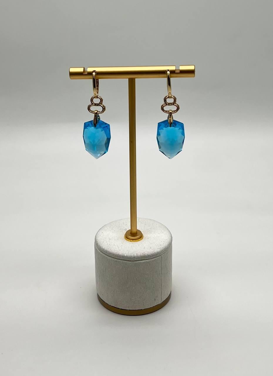 Discover the elegance of these exquisite earrings.
Featuring striking blue faceted gemstones, these earrings captivate with their vibrant hue and intricate cut.
The design includes delicate loops encrusted with shimmering diamonds, adding a touch of