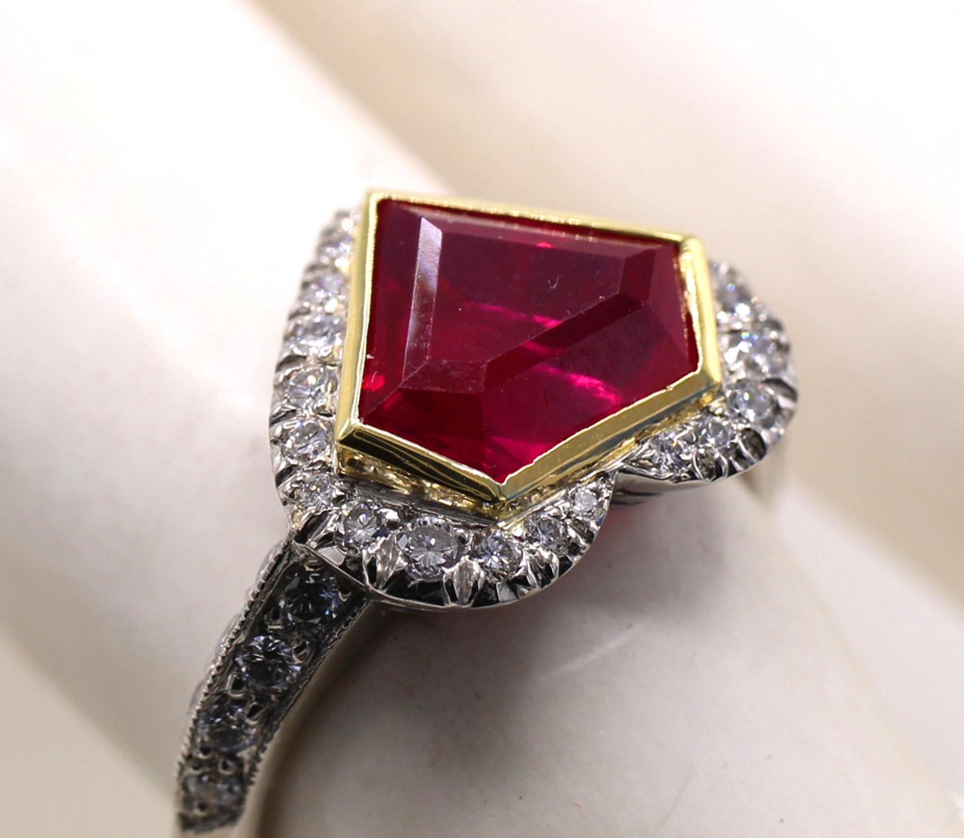 Uniquely designed for a unique gem stone, this beautiful and masterfully handcrafted ring has the outline of a heart shape with and inner yellow gold bezel in the shape of a shield or diamond. The center piece is  a pigeon blood red beautiful Burma