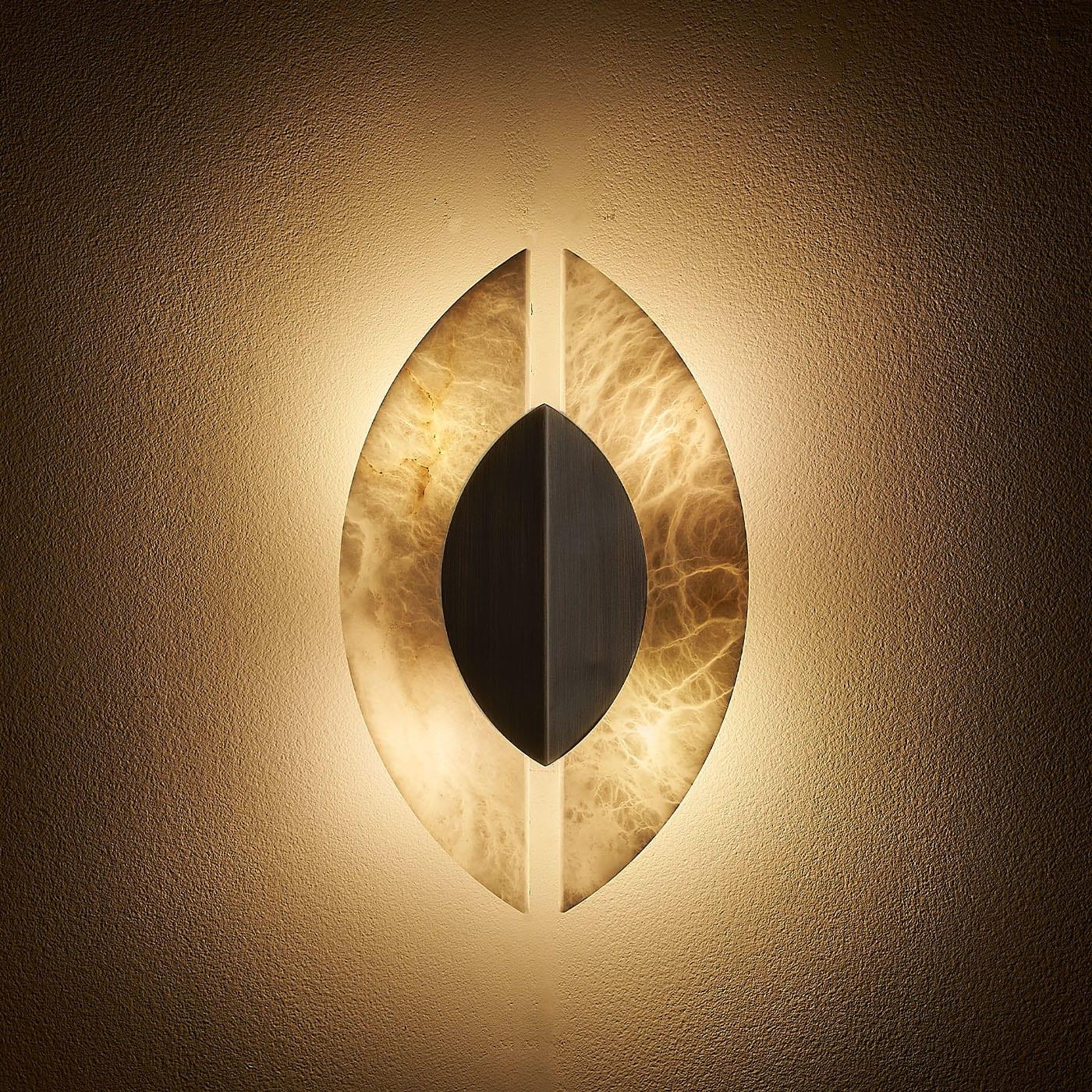 The Shields wall sconce is designed to evoke a sense of medieval history and warrior culture, with its brushed bronze and alabaster materials reminiscent of ancient shields. The use of alabaster also adds a natural, textured element to the design,