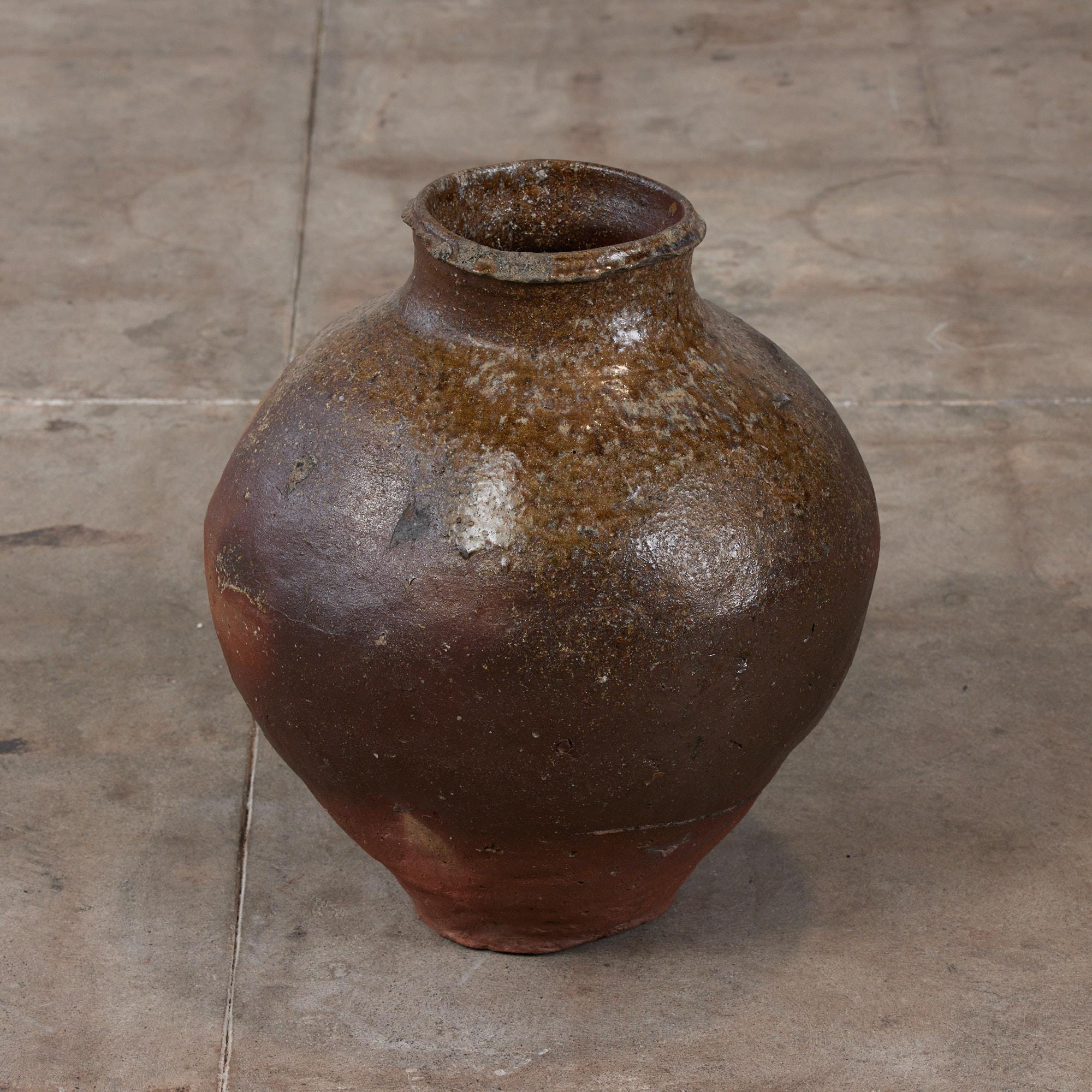 Japanese ceramic vessel from Shiga, Japan. This piece gains its unique glaze and irregularities from the firing process in which wood is added to the kiln. The ash that is produced then falls on the vessel offering shades of yellow and brown while