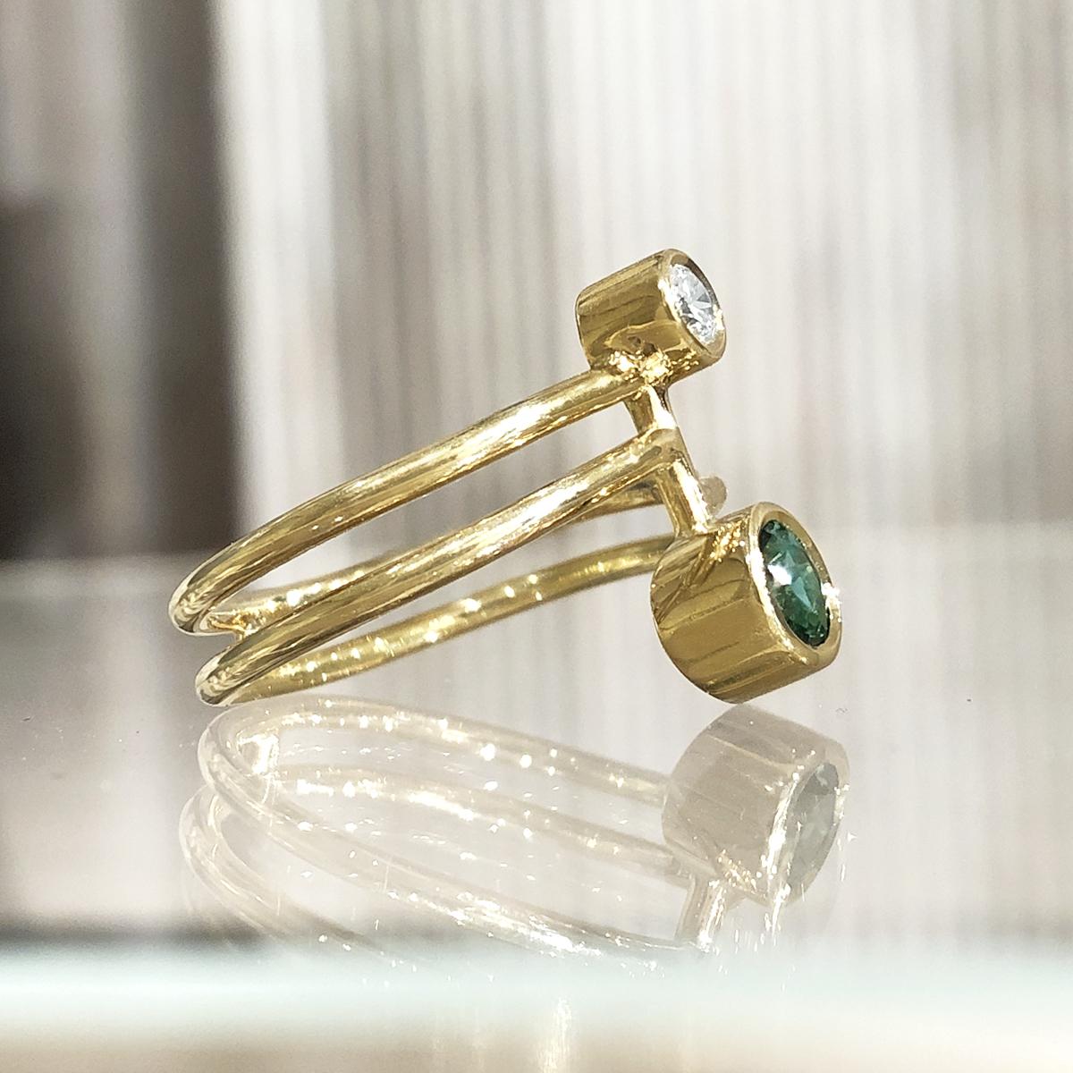 One of a Kind Double Stone Ring hand-fabricated in London by acclaimed jewellery maker Shimell and Madden in high-polished 18k yellow gold featuring a stunning 5mm faceted round blue green tourmaline accented by a 0.14 carat round brilliant-cut