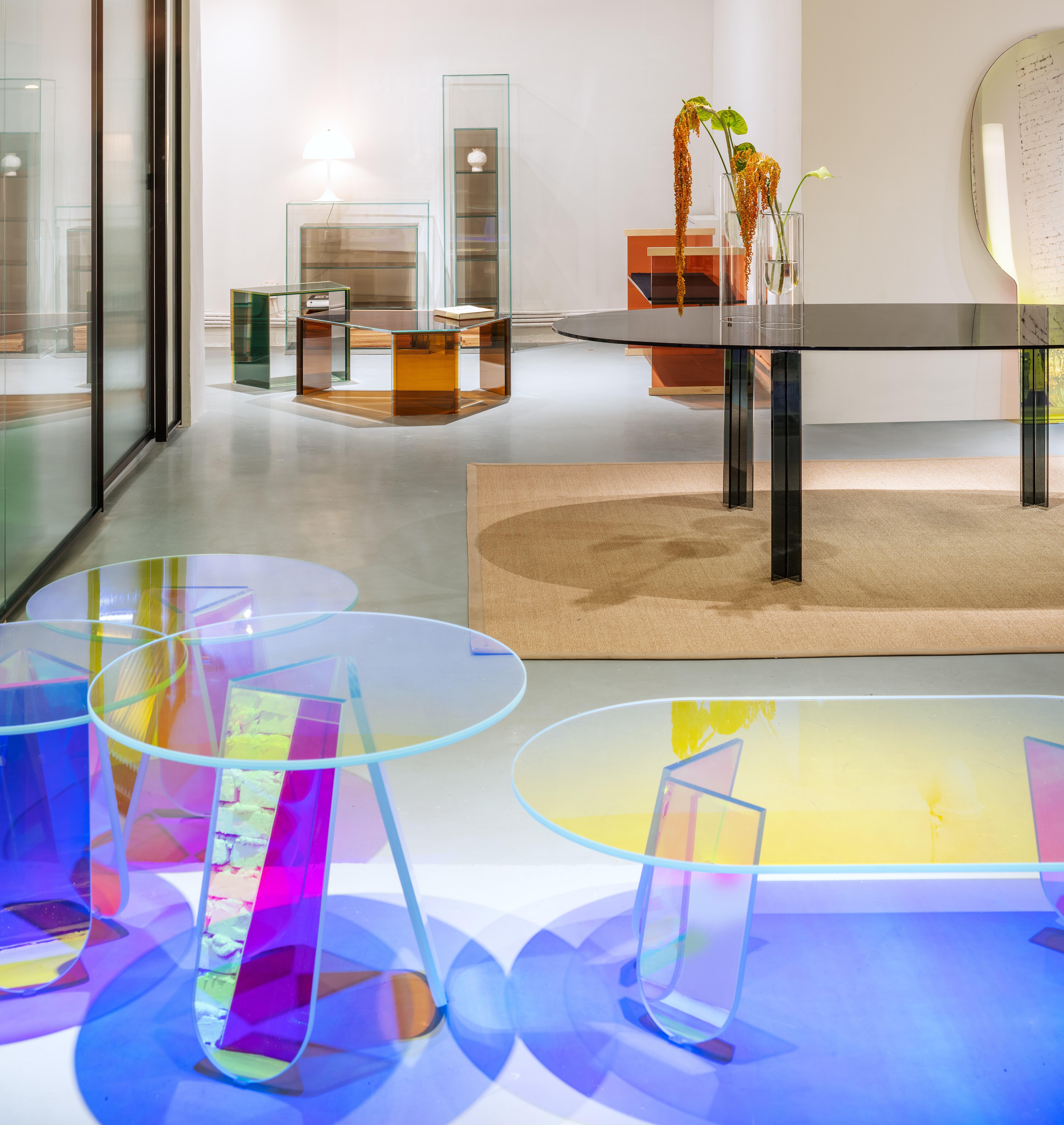 Il tavolino Shimmer è mostrato qui nella versione in vetro laminato e incollato e nelle dimensioni ridotte dei tavolini rettangolari. La collezione è disponibile in tavoli alti, tavoli bassi e console in vetro stratificato e incollato,