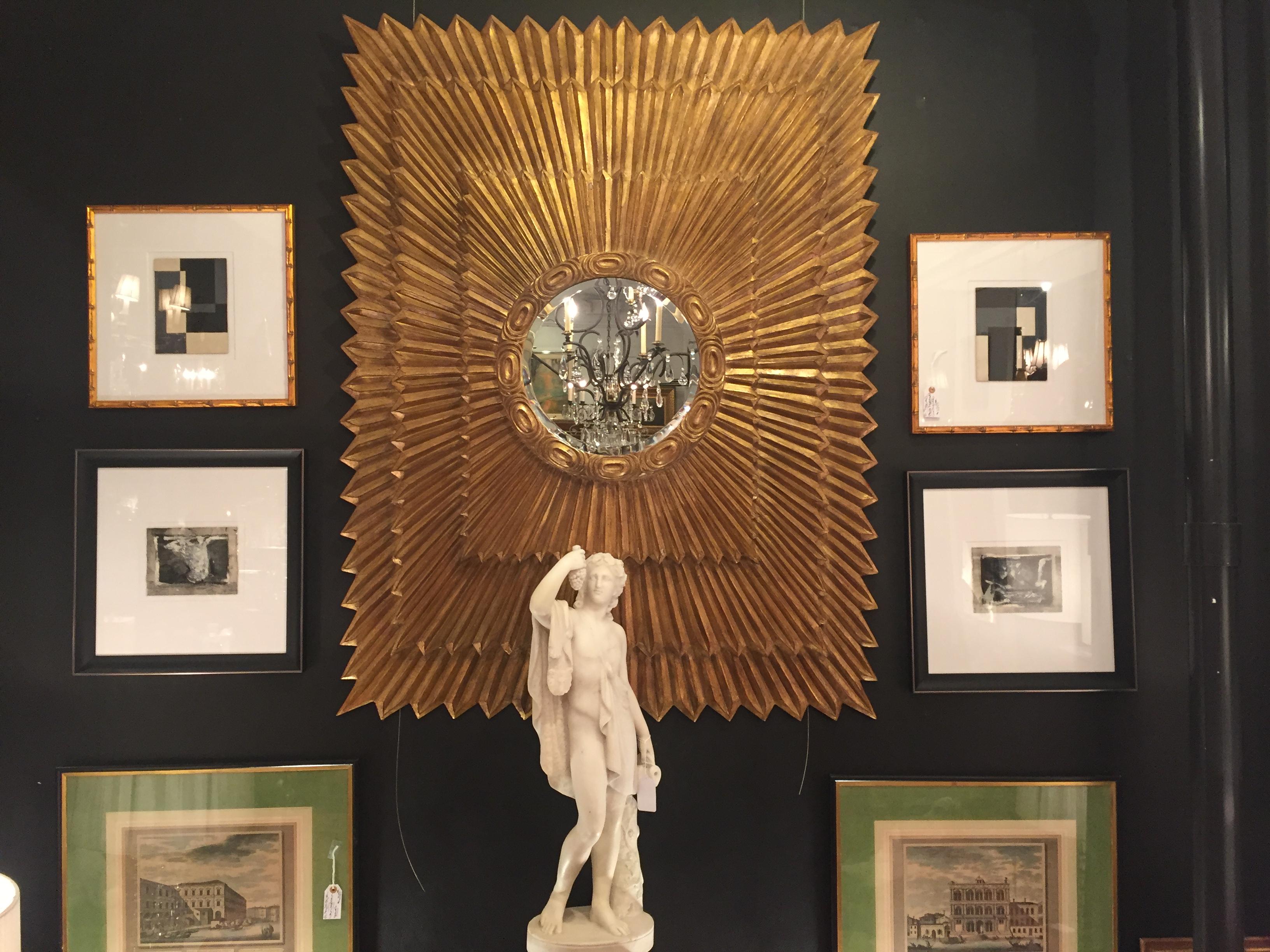 The show stealer mirror because of its monumental size and glitzy giltwood sunburst motif, having three layered rectangles in graduated sizes and a small round mirror in the centre.