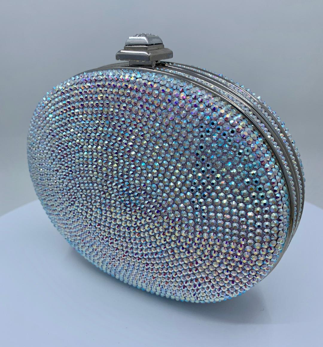 Exquisite handmade couture designer, Judith Leiber, shimmering crystal oval shaped minaudiere evening bag or evening clutch is completely covered in a rainbow of opalescent crystals. Silver toned metal frame with metallic silver leather lined