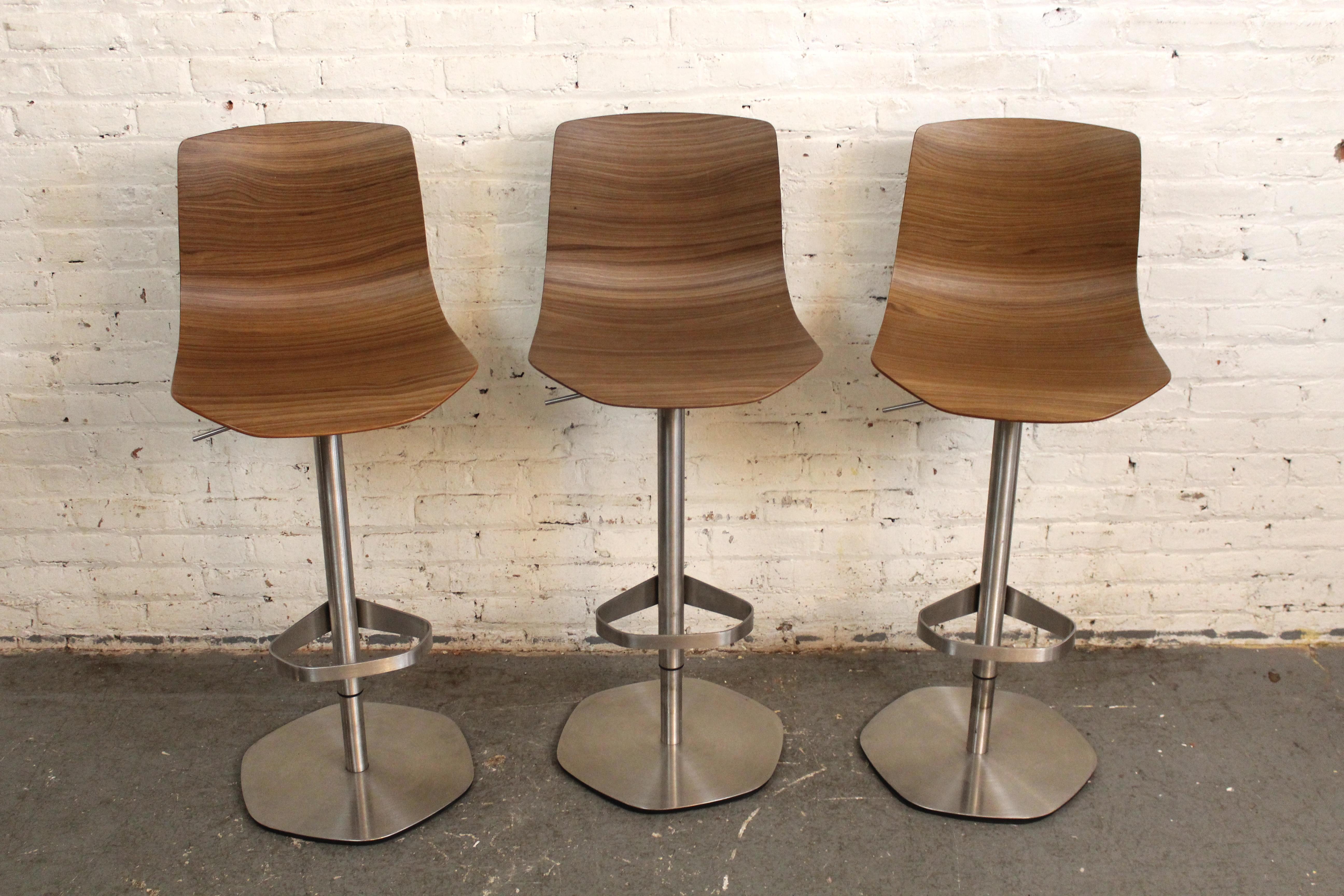 Made in Thailand and designed by Shin Azumi for Case, featuring a delicate molded walnut seat set on a strong stainless steel base. Stools are fully rotating, and adjust from 39