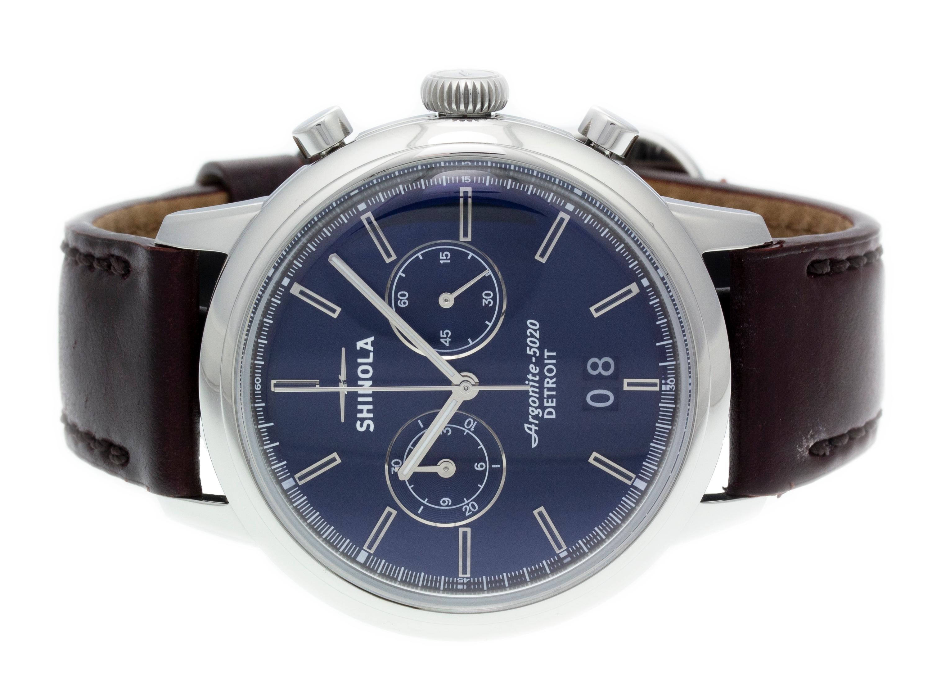 Stainless steel Shinola The Bedrock Chrono quartz watch with a 42mm case, midnight blue dial, and brown leather strap with tang buckle. Features include hours, minutes, seconds, date, and chronograph. Comes with a Shinola Box & Manual and 2 Year