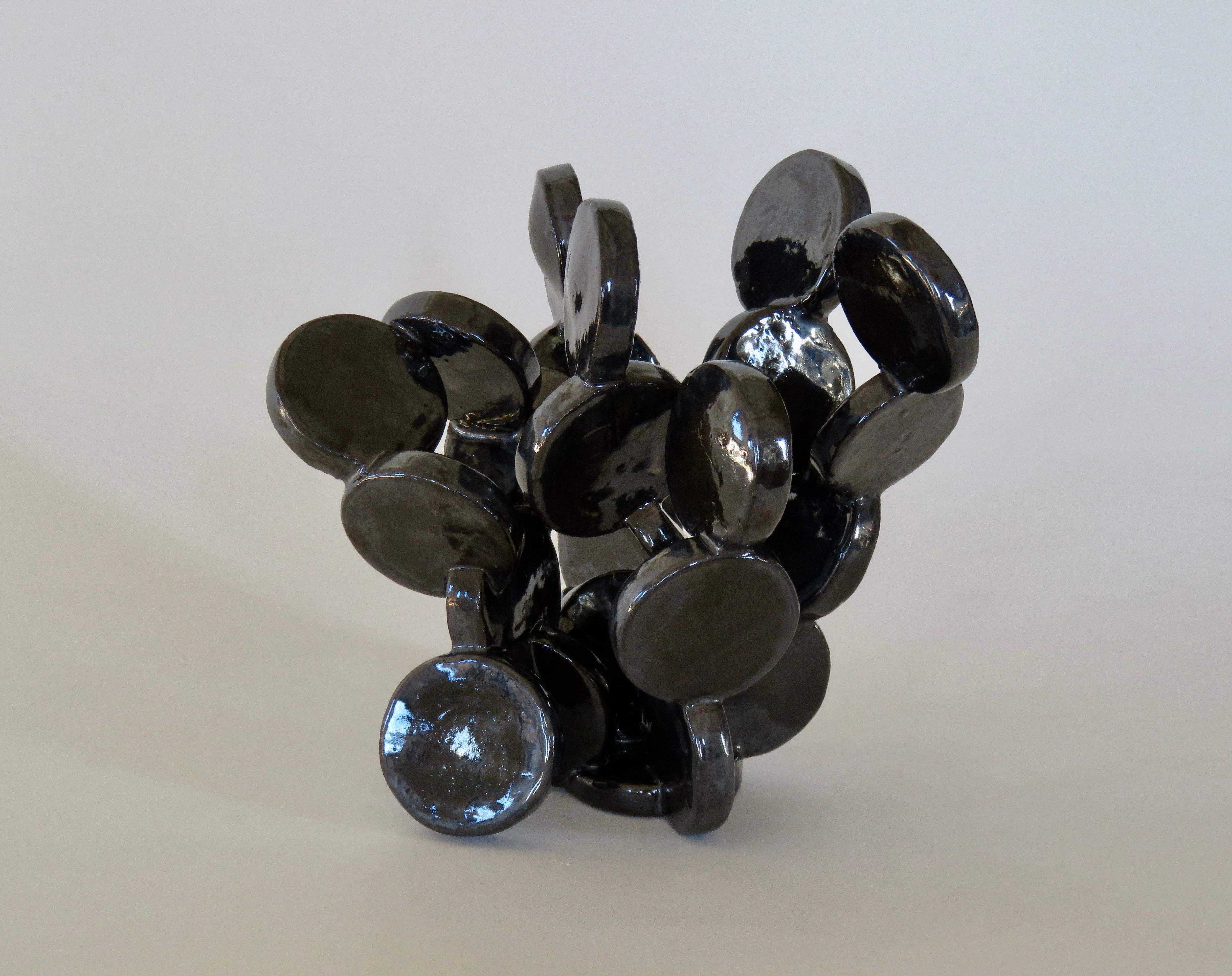 More than 20 small ceramic discs cutout and connected by hand, glaze fired into a unique, shiny black table-top sculpture. Reminiscent of a favorite plant or molecular structure, different from every angle. Fully handmade, no two are ever