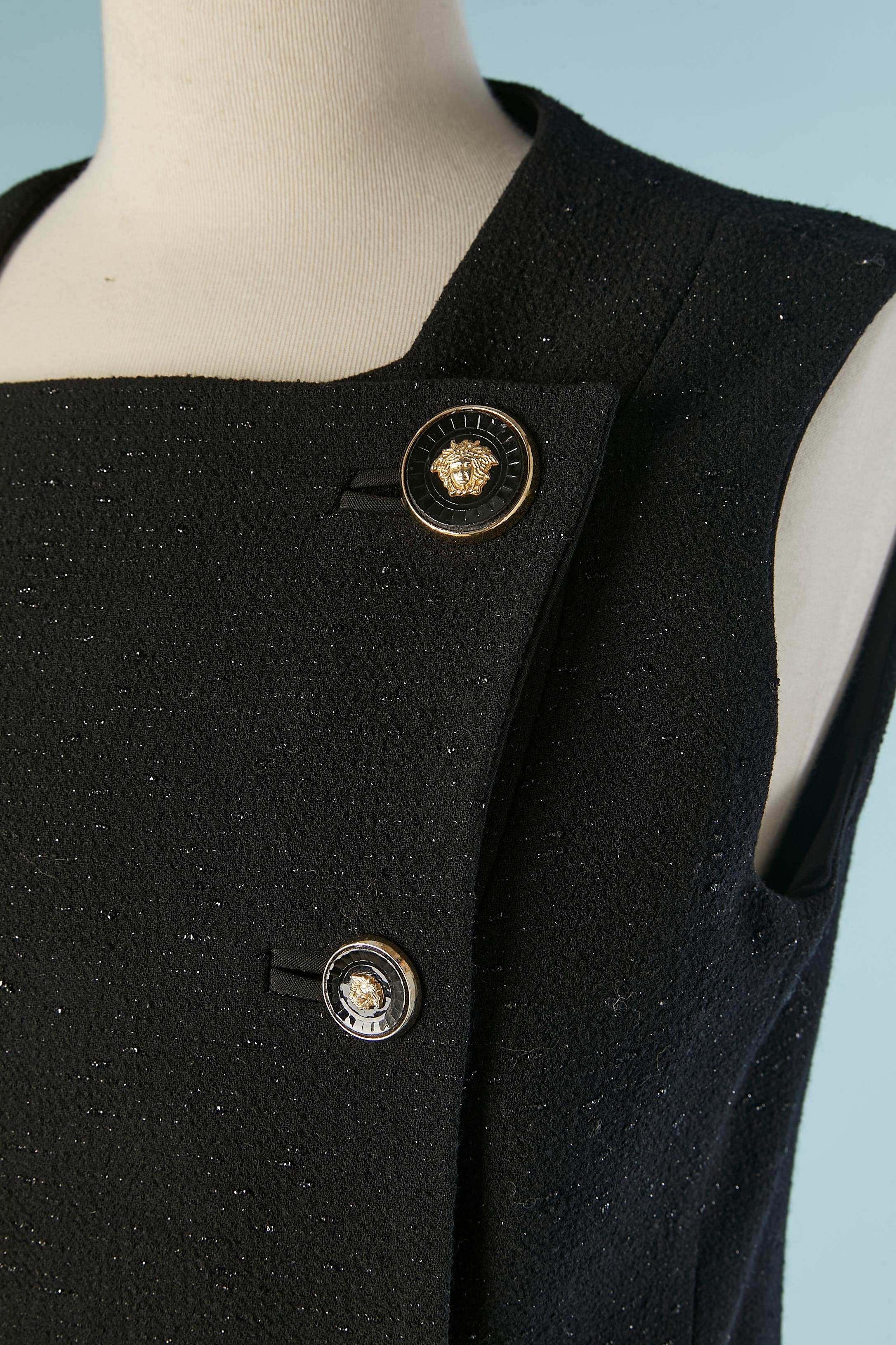 Giacca nera lucida a doppio petto senza maniche con bottone Medusa e chiusura ad asola sul centro della fronte. Composizione del tessuto principale: 97% lana, 3% poliestere. Fodera in rayon. Chiusura a scatto all'interno. 
TAGLIA 40 (Fr) M