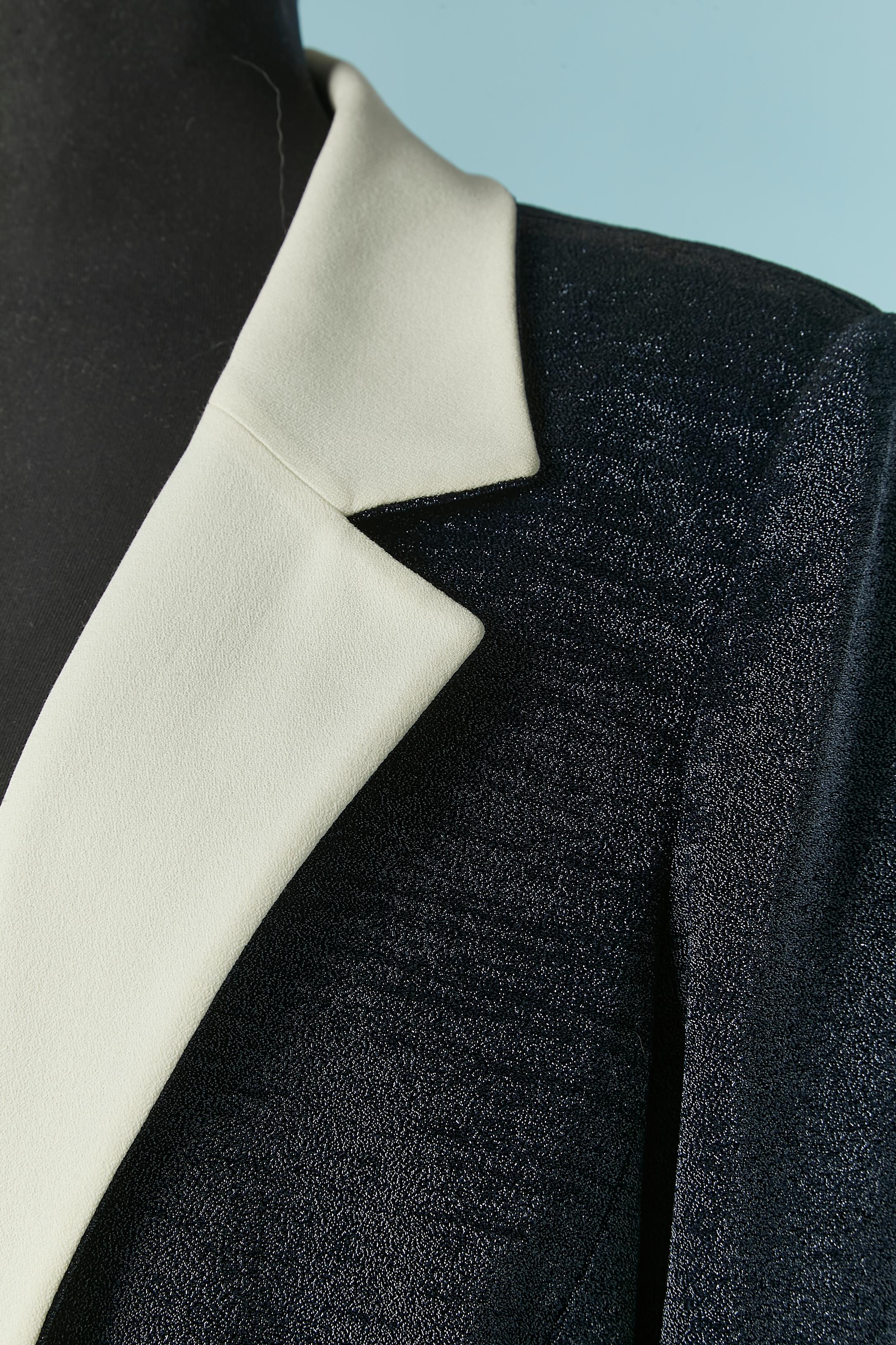 Shiny navy blue jacket with white collar and cuffs. Fabric composition: 95% nylon, 5% elastane. Branded Lining composition: 41% acetate, 30% cotton, 29% rayon. 
Pocket on both side with button and buttonhole closure. Shoulder pad. 
Pencil mark on