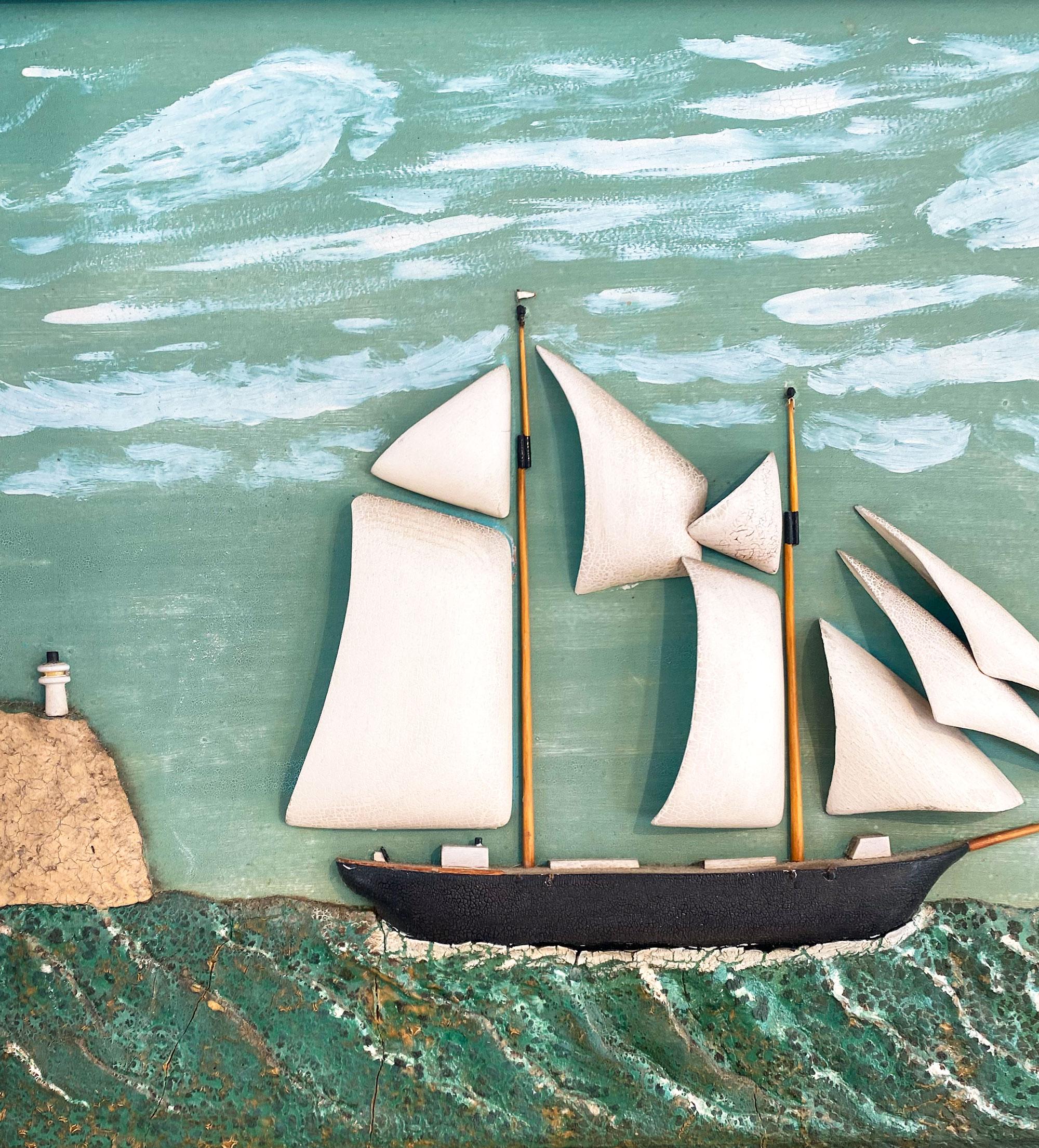 Ship diorama depicting a two mast ship with two lighhouses in the background, one of them on top of a rock. The sails, hull, rock, and lighthouse are carved from wood, the sea is painted plaster and the diorama is mounted on a masonite. Oak from