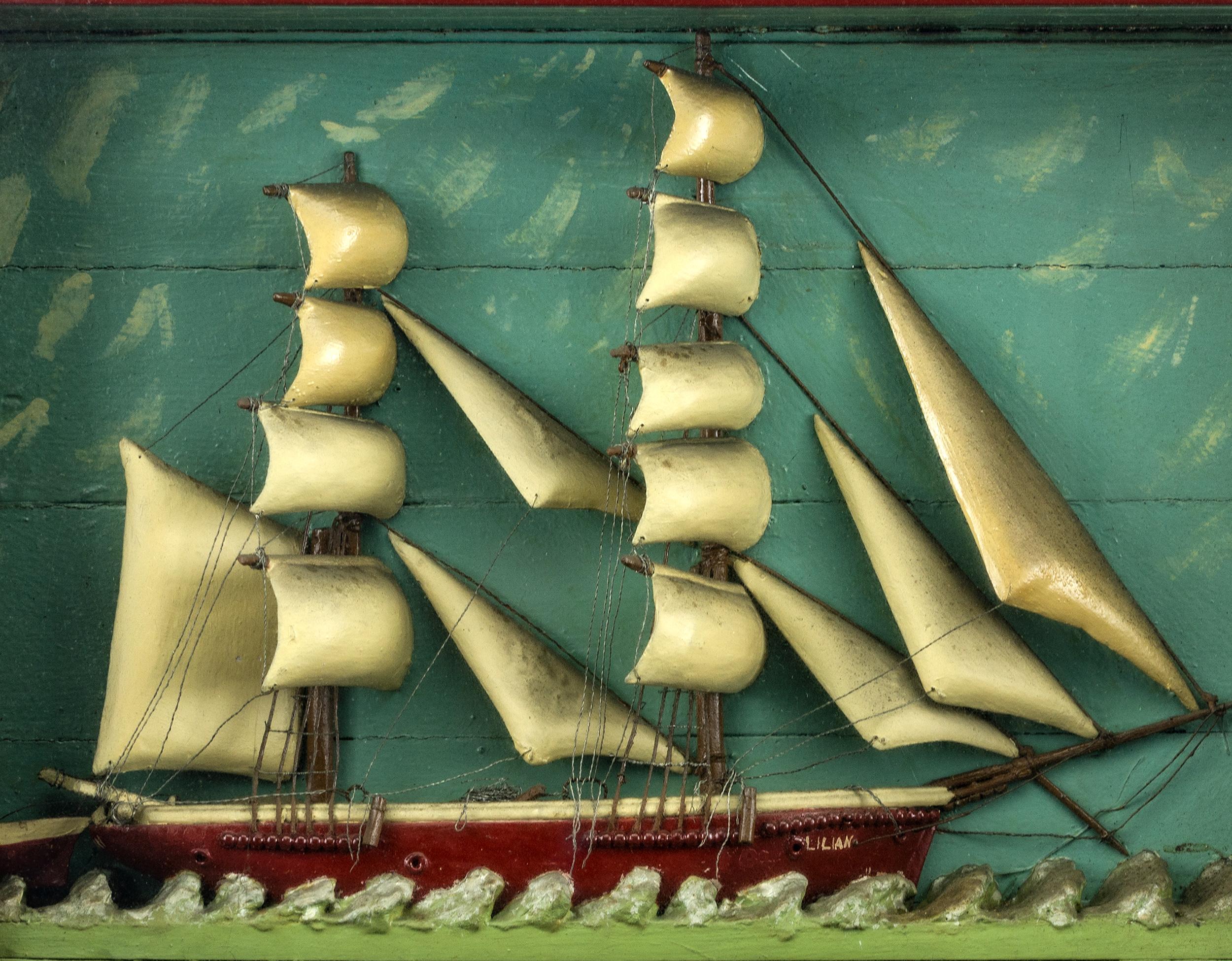 Shadow box ship diorama of two masted ship Lillian with matching rowboat, carved wooden sails and hull. Mounted in a red painted stepped frame. A great and
unusual ship diorama in untouched condition, New England, circa 1900.