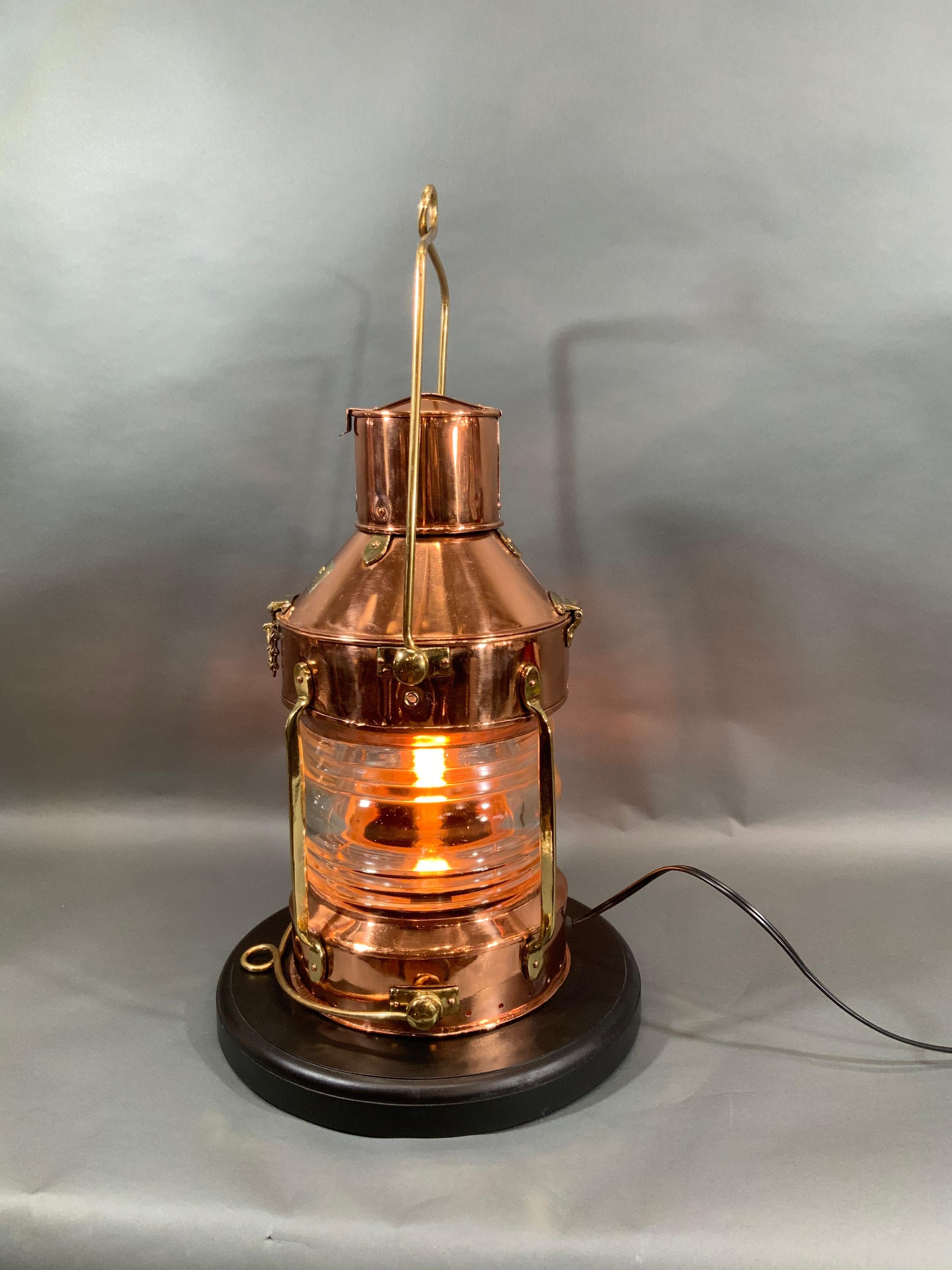 Antique copper and brass ship's anchor lantern with meticulously polished and lacquered finish. Wired for home use. Fitted with a glass Fresnel lens. Brass makers badges from R.C. Murray 37 Cavendish St, Glasgow. Mounted to a thick mahogany base.