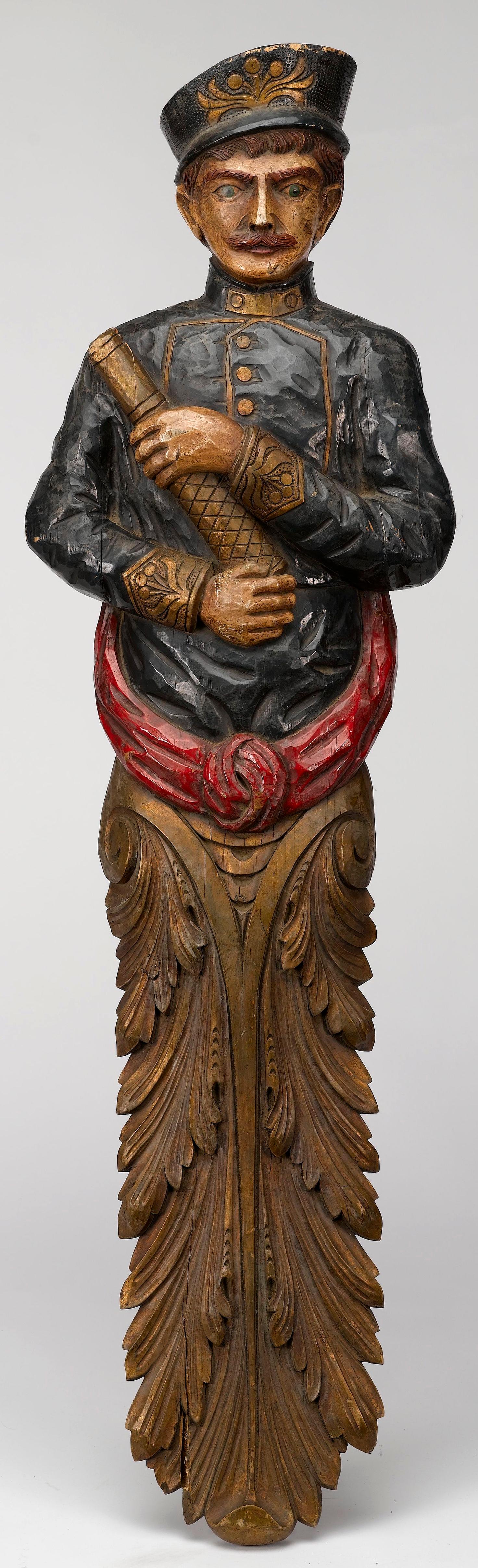 This is a beautifully crafted large antique ship figurehead, hand carved and hand painted from the 1930s. Carved in the shape of a male ship captain, the figurehead wears a blue and gold jacket, a captain’s hat, and holds a gold telescope in his