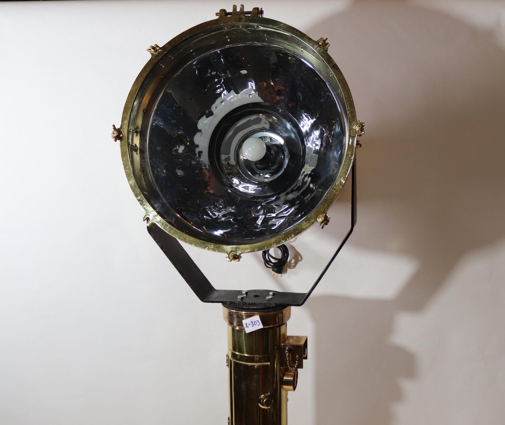 Tripod mounted marine spotlight. Fitted to a maritime compass pedestal, this large Yoke mounted ships floodlight had been meticulously polished and lacquered. With glass lens and polished besel. Recently rewired and fitted with a new socket, circa