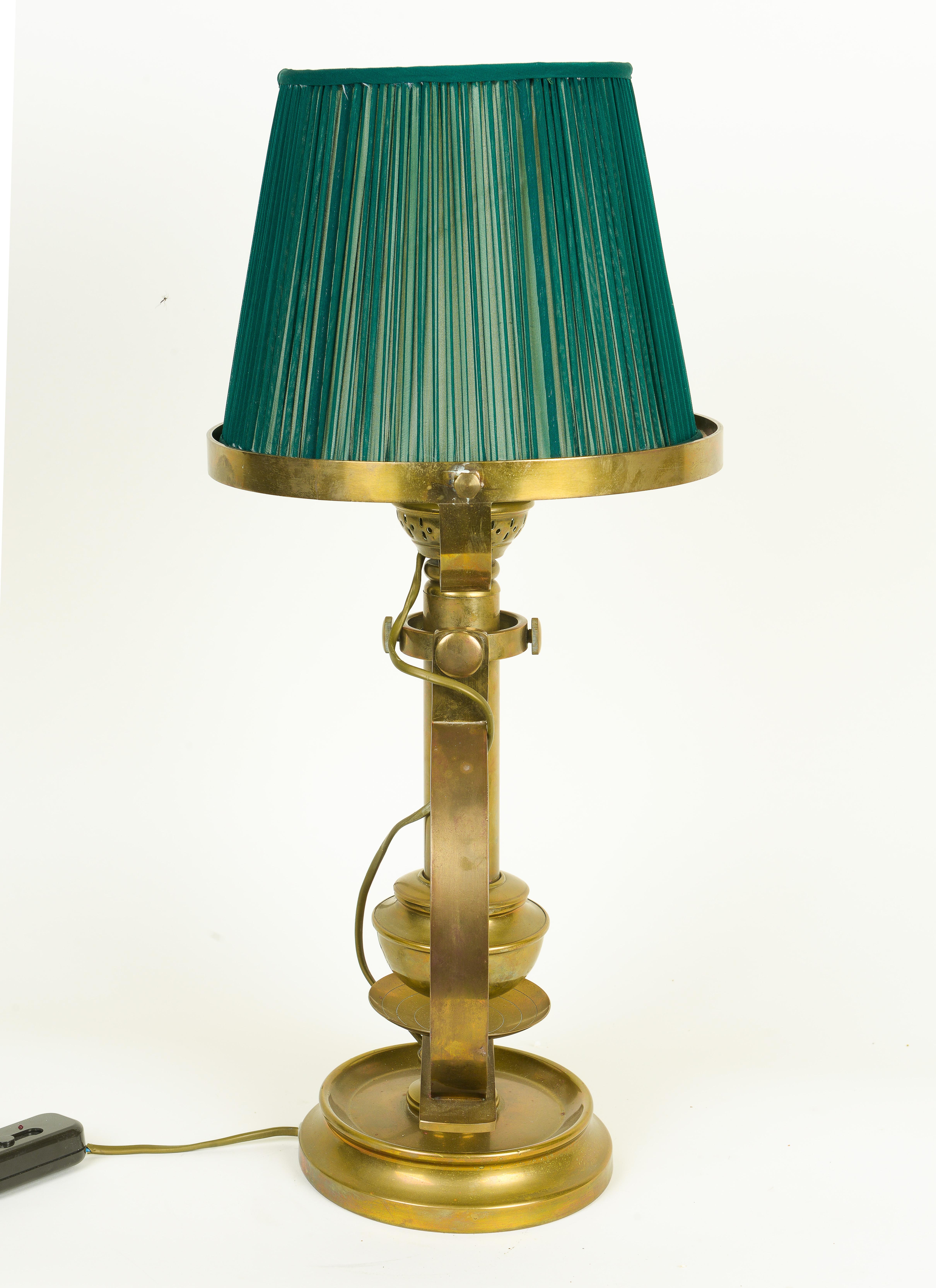 Of substantial form with brass-trimmed green silk shade; designed with a gimbal support that allows the light to stay level even when a ship pitches and rolls.