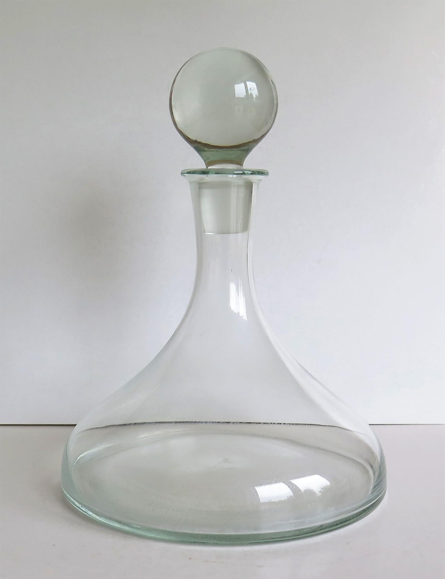 This is a ship's glass decanter with a wide base made from heavy lead glass having a soft light grey color with a globe stopper and with a fluid capacity of about 1.25 litres, all dating to circa 1920.

Most of these ship's glass decanters are