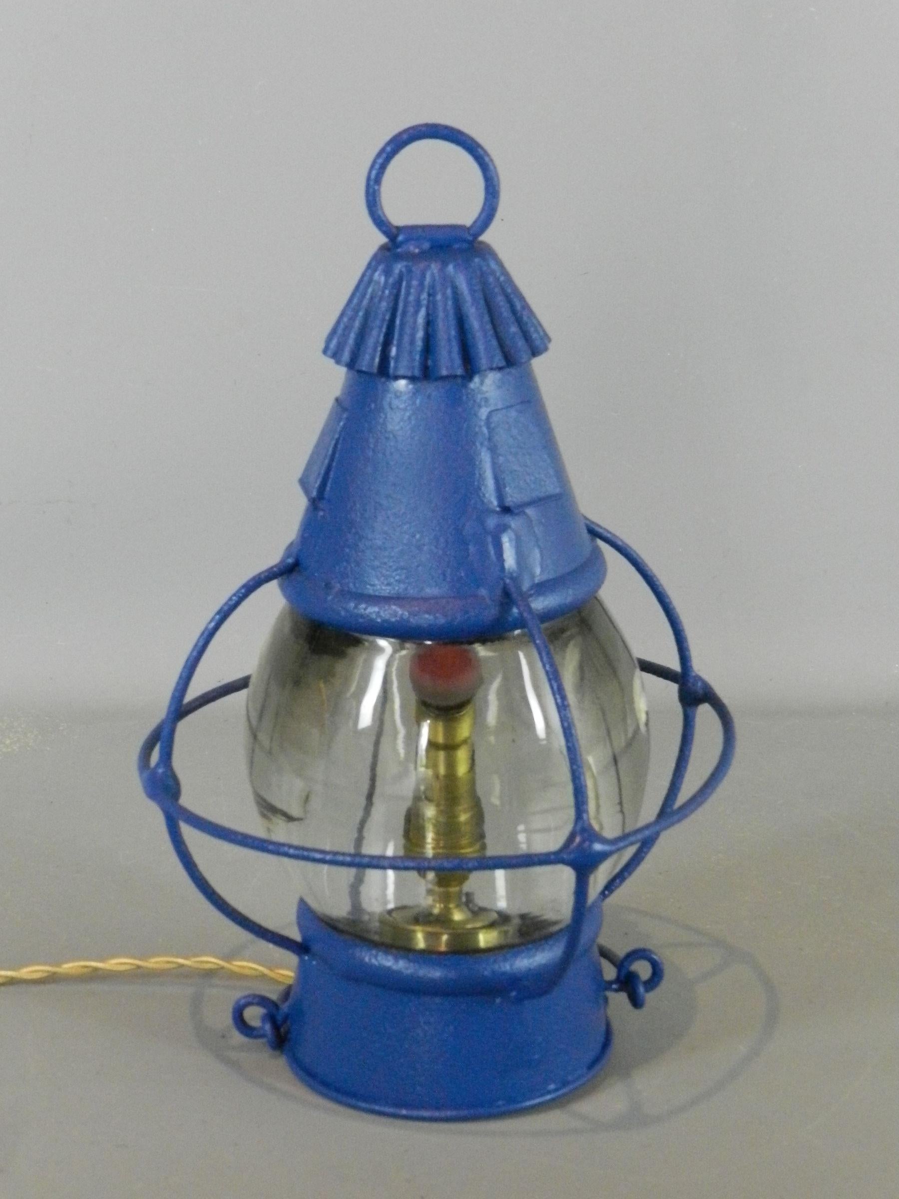 Une lanterne à huile de bateau d'origine qui a été convertie à l'électricité et qui peut être utilisée comme lampe de table ou lampe suspendue.

Le verre présente des bulles et des inclusions correspondant à son âge.

La lanterne a été repeinte et