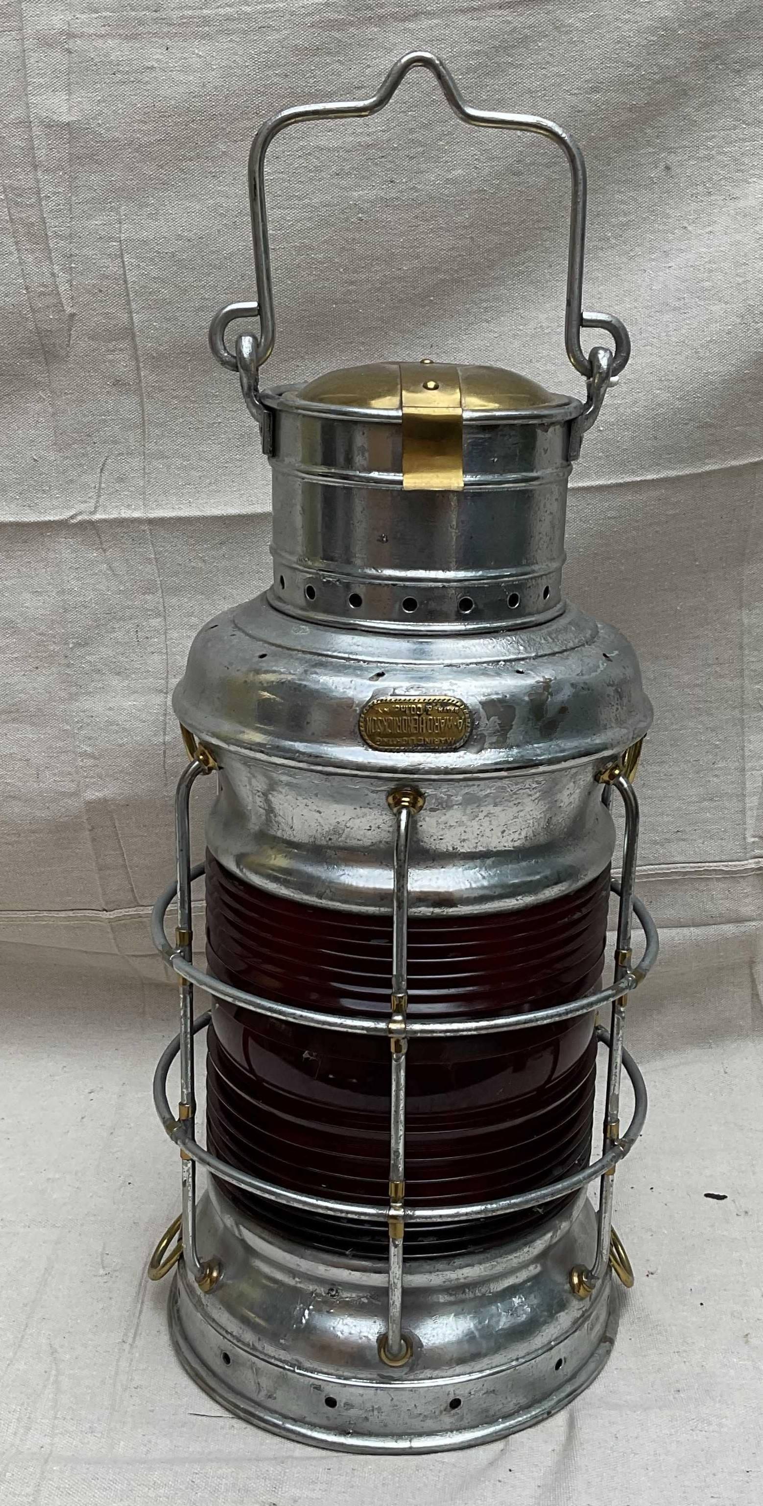 Steel case ships lantern by Brooklyn New York maker A Ward Hendrickson. With red ruby lens. Hinged brass chimney cap. Carry handle and protective cage. No burner. 20Tx10D