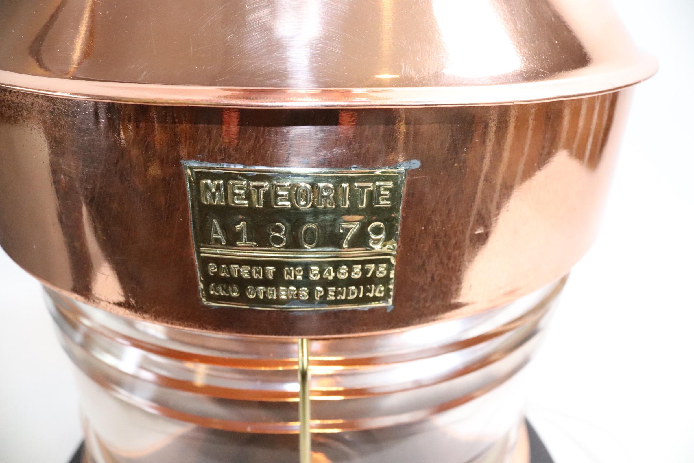 Outstanding copper ships masthead lantern by the English firm Meteorite. With clear Fresnel glass lens, brass makers badge with serial number A18079. With heavy brass hoisting handle. Mounted to a thick custom wood base with dark finish. Wired with