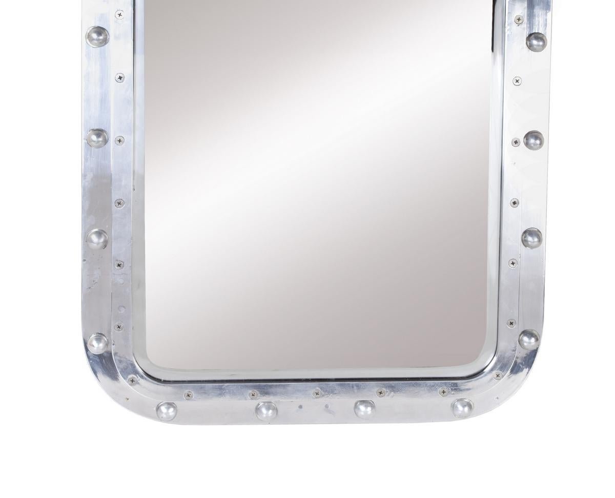 From a decommissioned ship, a chrome window converted to a wall mirror. Brackets have been added on all four sides on the back side so that it can be hung in either direction. The rivets have been put back in to provide a more complete look--the