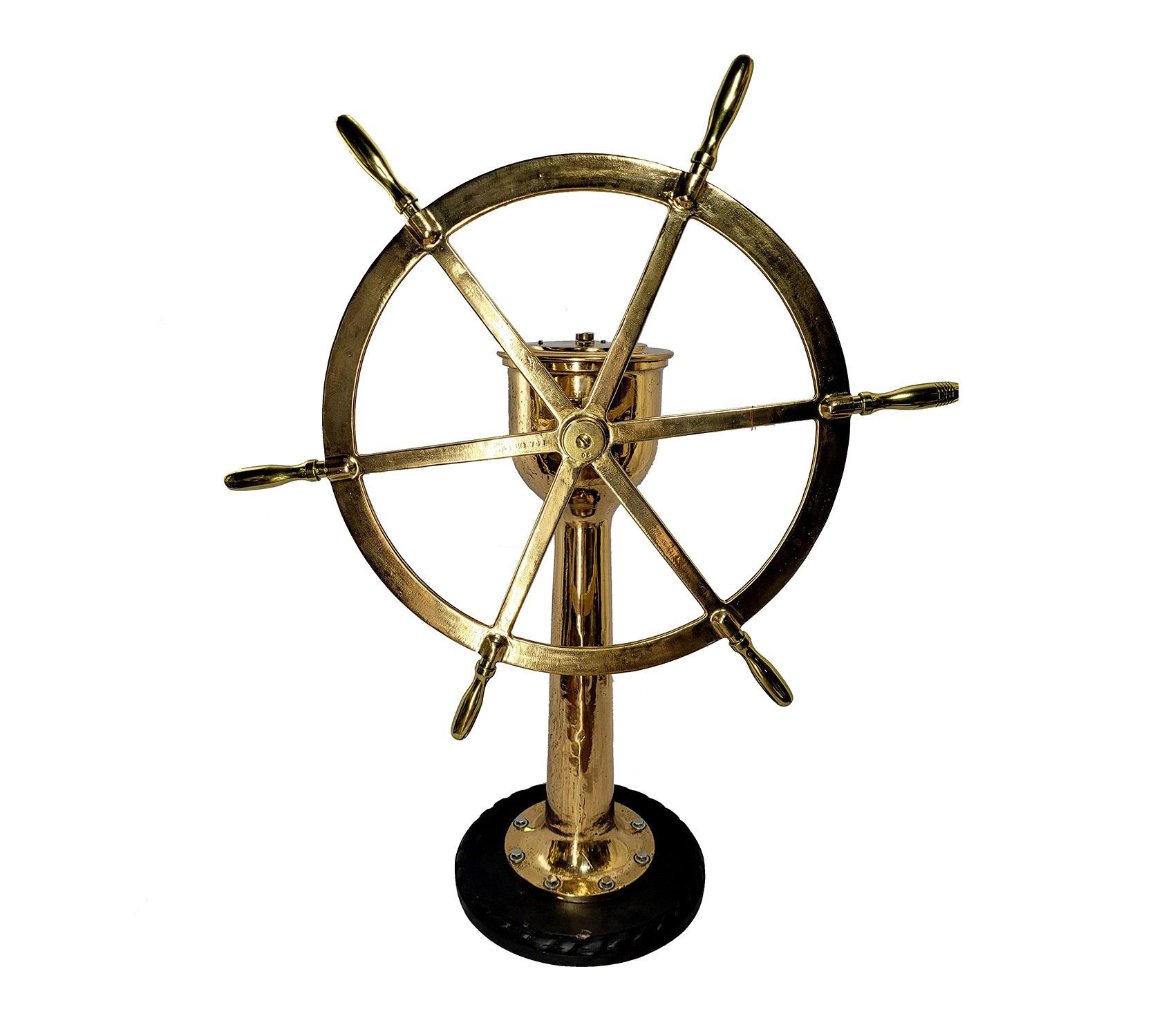 Solid brass six spoke ships wheel on pedestal. Very heavy piece, the head is engraved AE Steering Gear, American Engineering Company, Philadelphia U.S.A. with rudder indicator arrow and degrees on head also. Internal gears are still present and turn