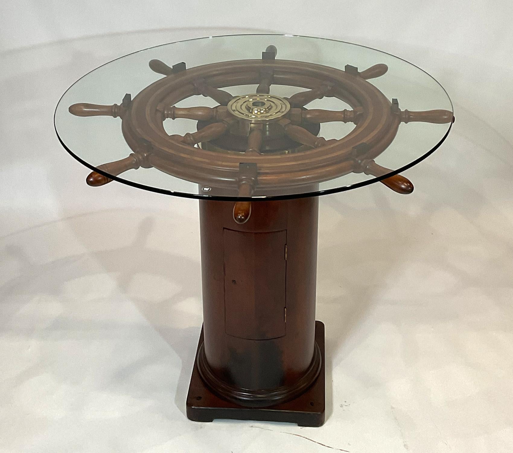 Antique American ships wheel mounted to a ships binnacle base creating an awesome bar height pub table. Perfect for two to four pub stools or chairs. The wheel has been expertly refinished. The brass hub has been highly polished and lacquered. This