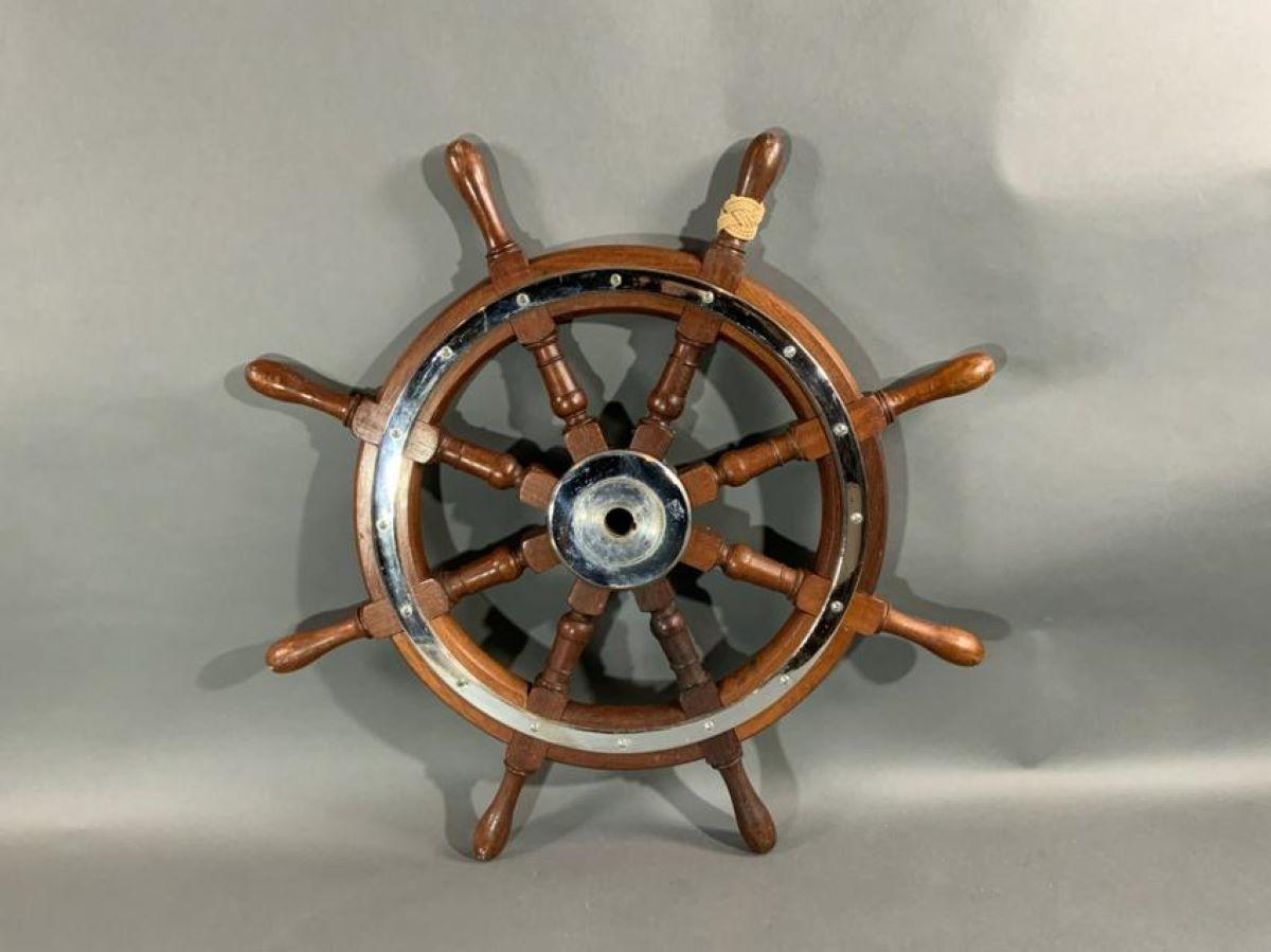 Eight spoke varnished mahogany ships wheel with chrome trim ring and center hub with cap. One handle has ropework.

Overall dimensions: Weight is 18 pounds. Measure: Diameter 30
