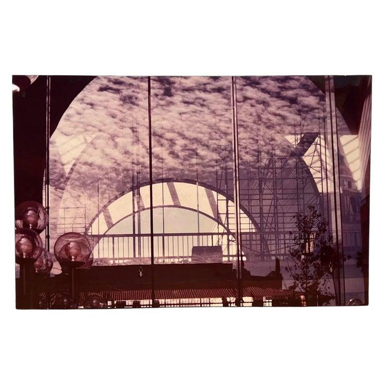 This photograph by Shirley Bleviss reveals a striking interplay of rounded forms and linear structures, all rendered in a restrained monochromatic palette. At its center, a luminous archway dominates the composition, serving as both portal and