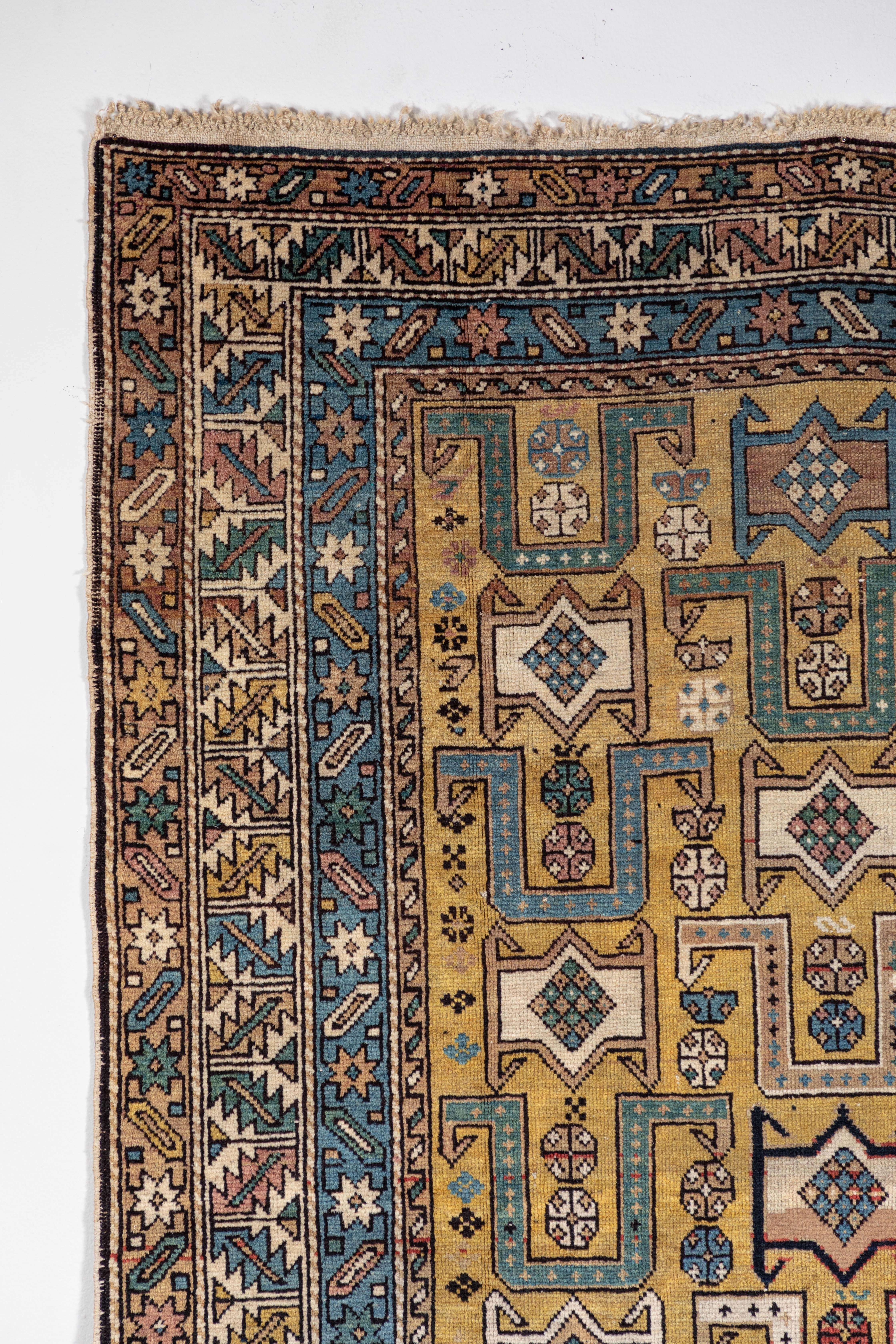 Antique Caucasian rug with unusual color palette. Even pile, ends complete, few small damages as shown. Gold background with geometric and floral motifs. Red, ivory, blue, green, pink, brown, orange.