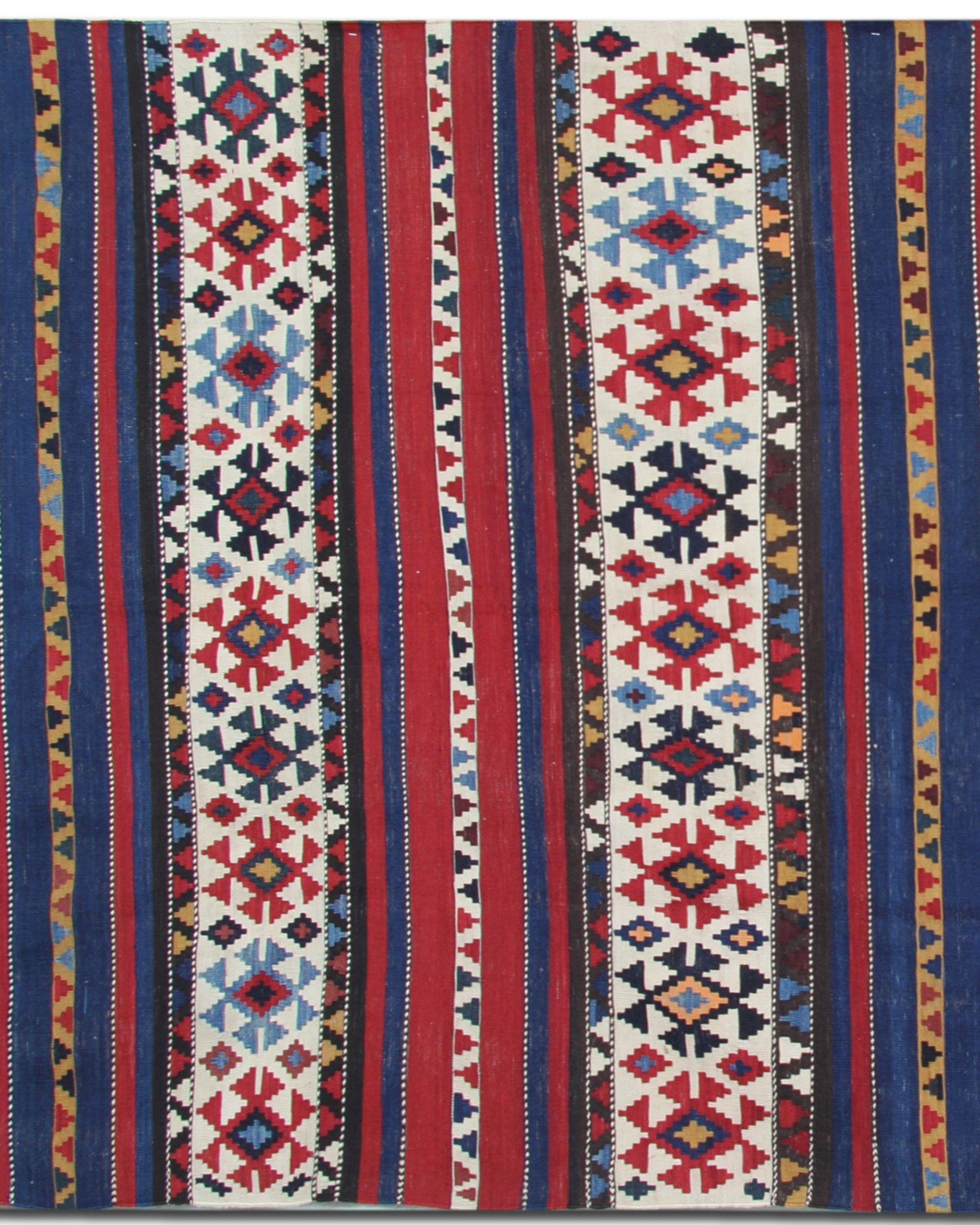 This Antique Caucasian Shirvan Kilim Rug is a vibrant and authentic 1940s tribal flatweave showcasing bold stripes, geometric symbols, and traditional folk-art motifs. Handwoven from natural wool, it blends rich colour with cultural heritage, making