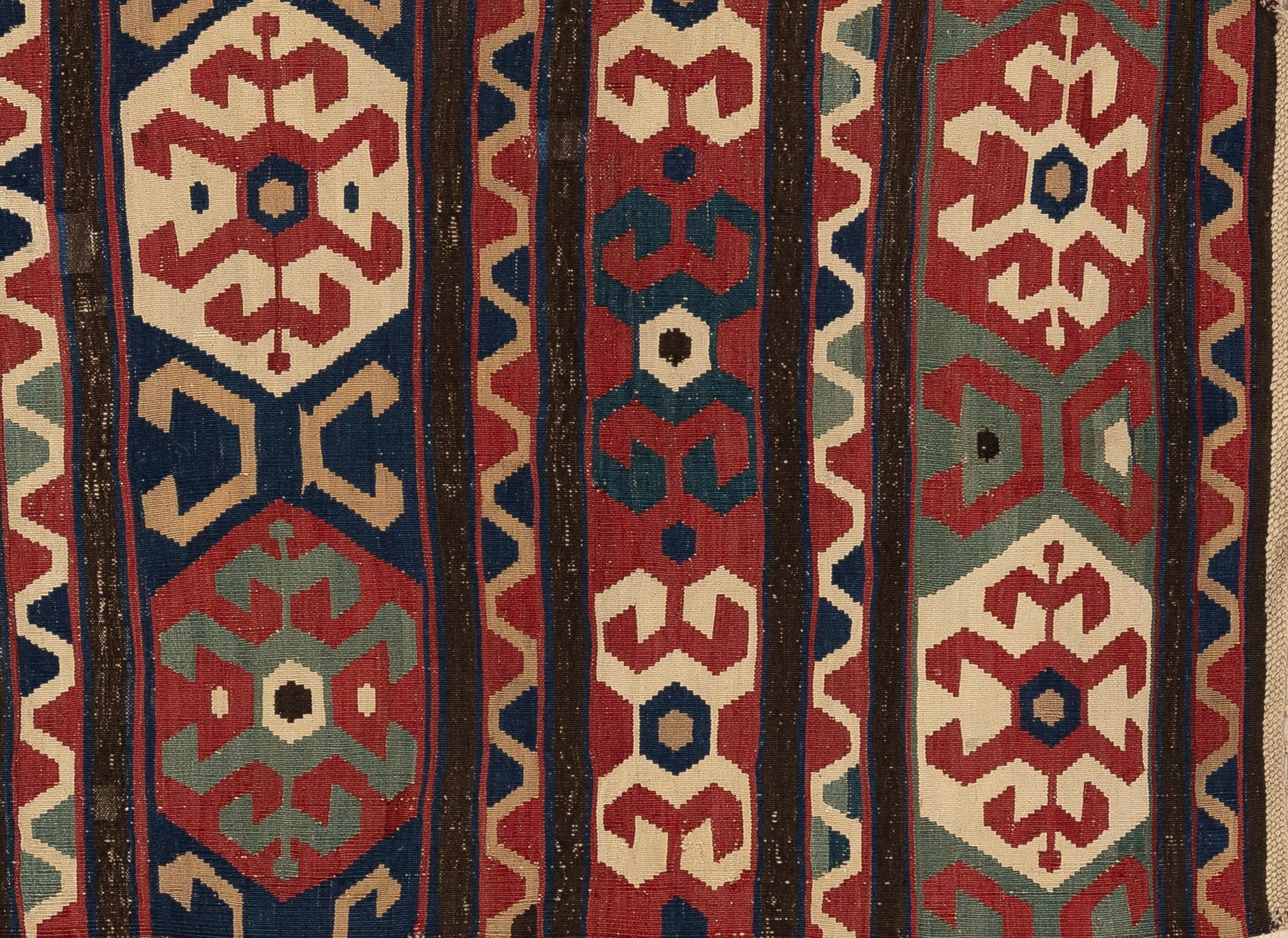 Ce tapis Shirvan, originaire de l'est du Caucase, est admiré pour sa structure finement tissée et son dessin géométrique vivant. Caractérisés par un dessin net, des proportions équilibrées et une utilisation harmonieuse des couleurs, les tissages de