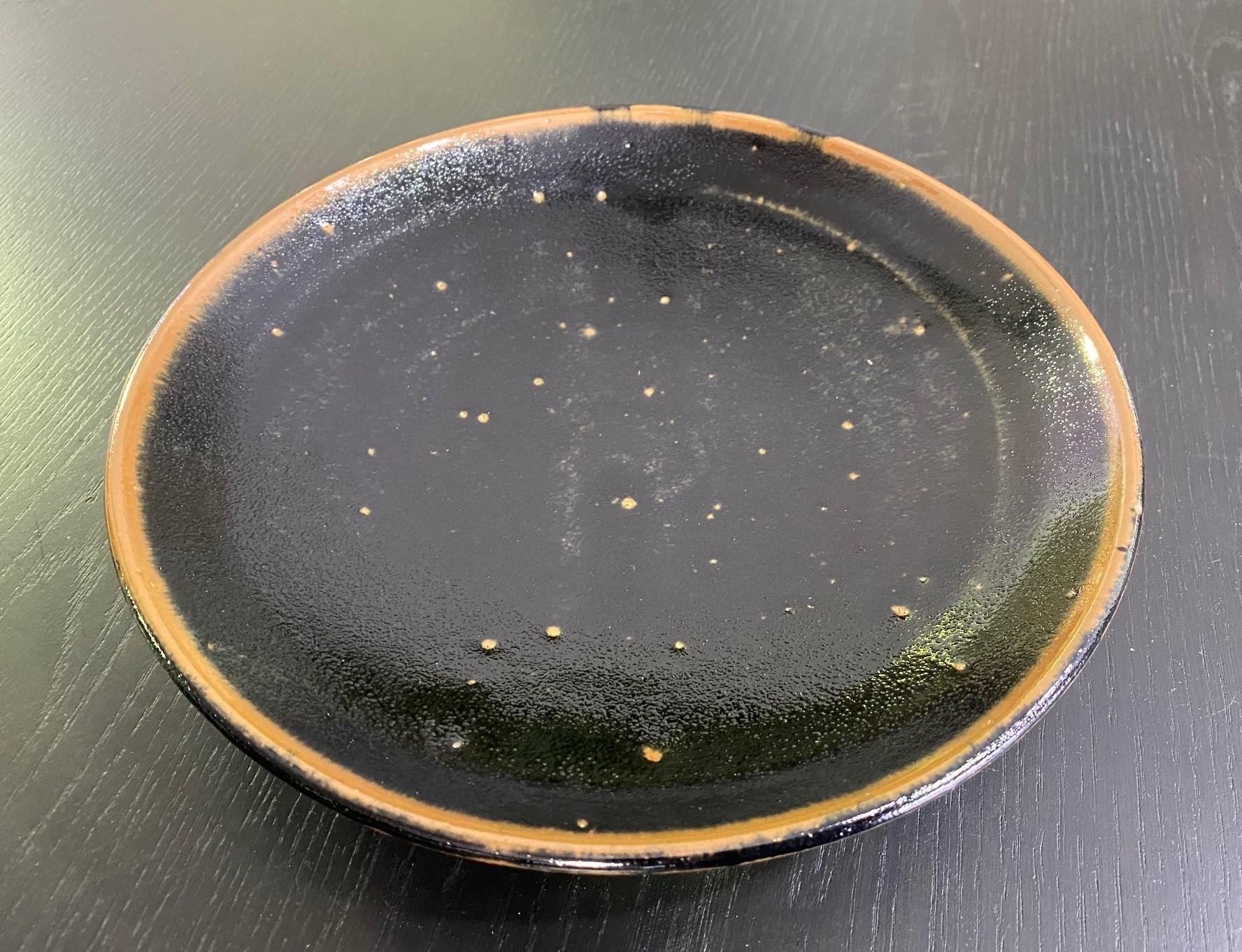 An exquisite, beautifully crafted, black-glazed plate by master Japanese potter Shoji Hamada. This is likely an early work based on the notation and the script on the box lid (see translation below) which we have been told by a Japanese expert is