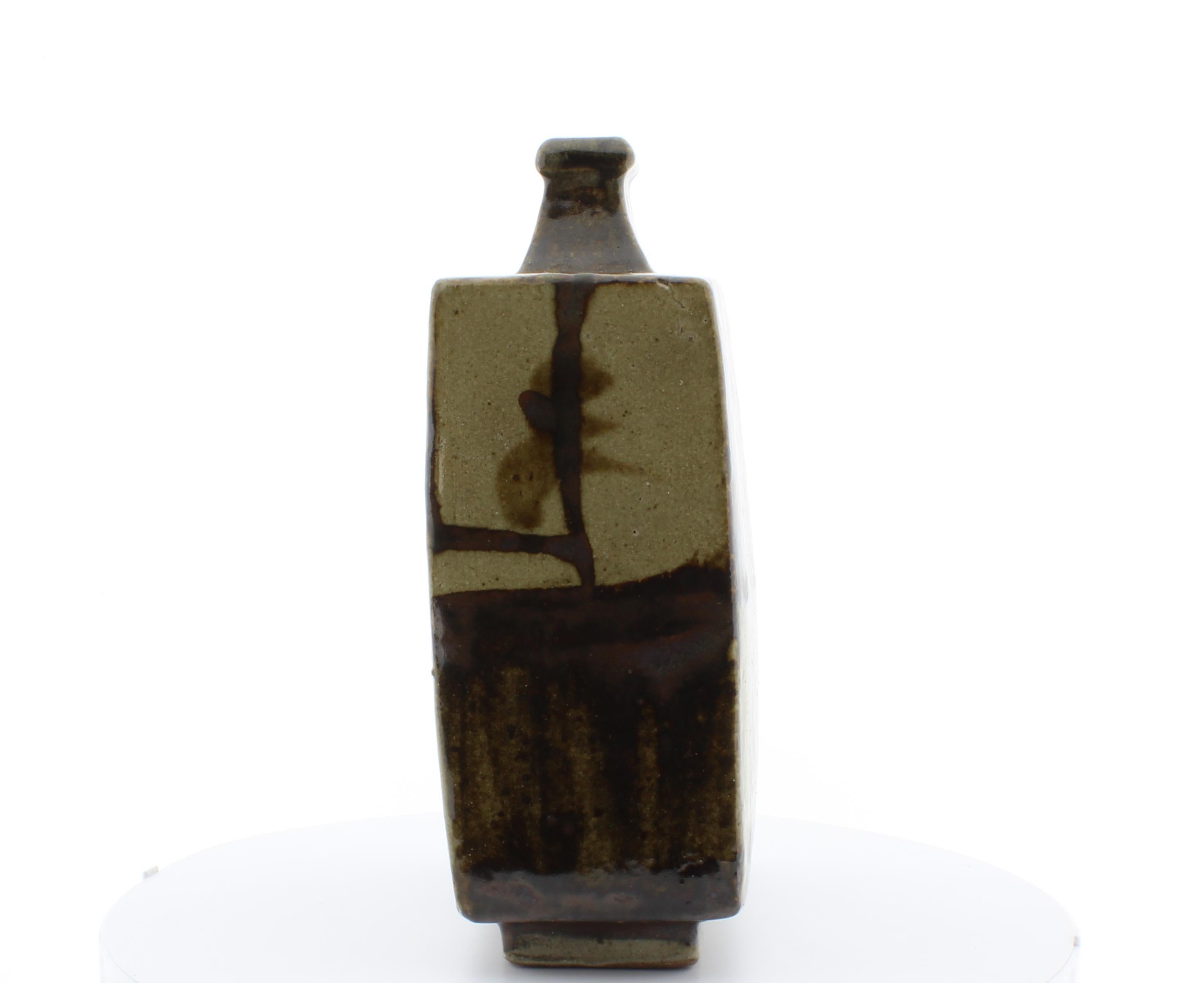 Artist: Shoji Hanada (1894-1978)
Title: Square Bottle Vase
Date: 20th century
Dimensions: (W) 14.8 (H) 23.3 (D) 7 cm
Condition: Cracks formed naturally from firing process.

A square shaped bottle vase with ash glaze and tetsu-e iron-oxide brushwork