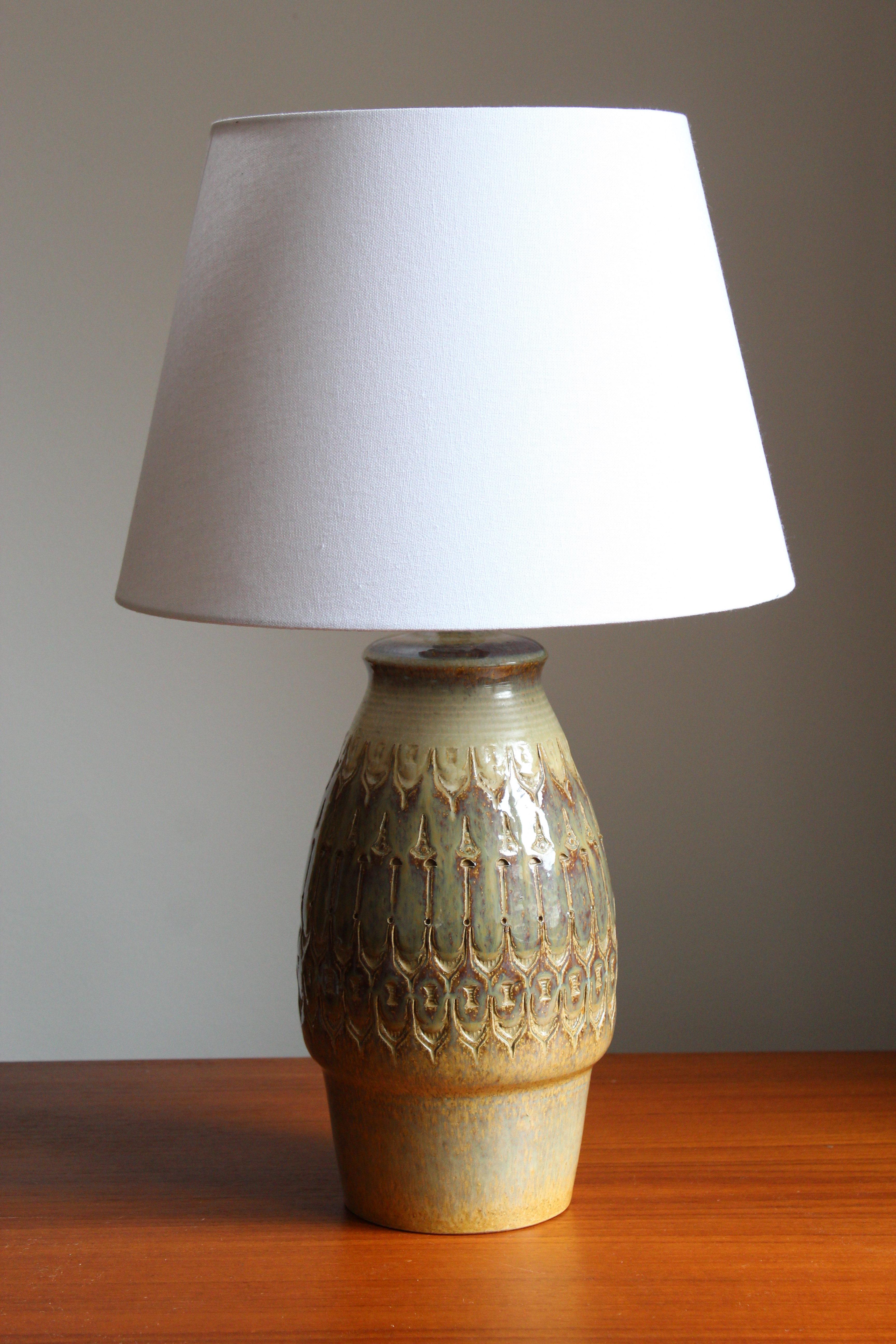 A large table lamp produced by Søholm Keramik, located on the island of Bornholm in Denmark. Features a highly artistic glazed and incised decor.

Sold without lampshade. Stated dimensions exclude the lampshade.

Glaze features brown-green
