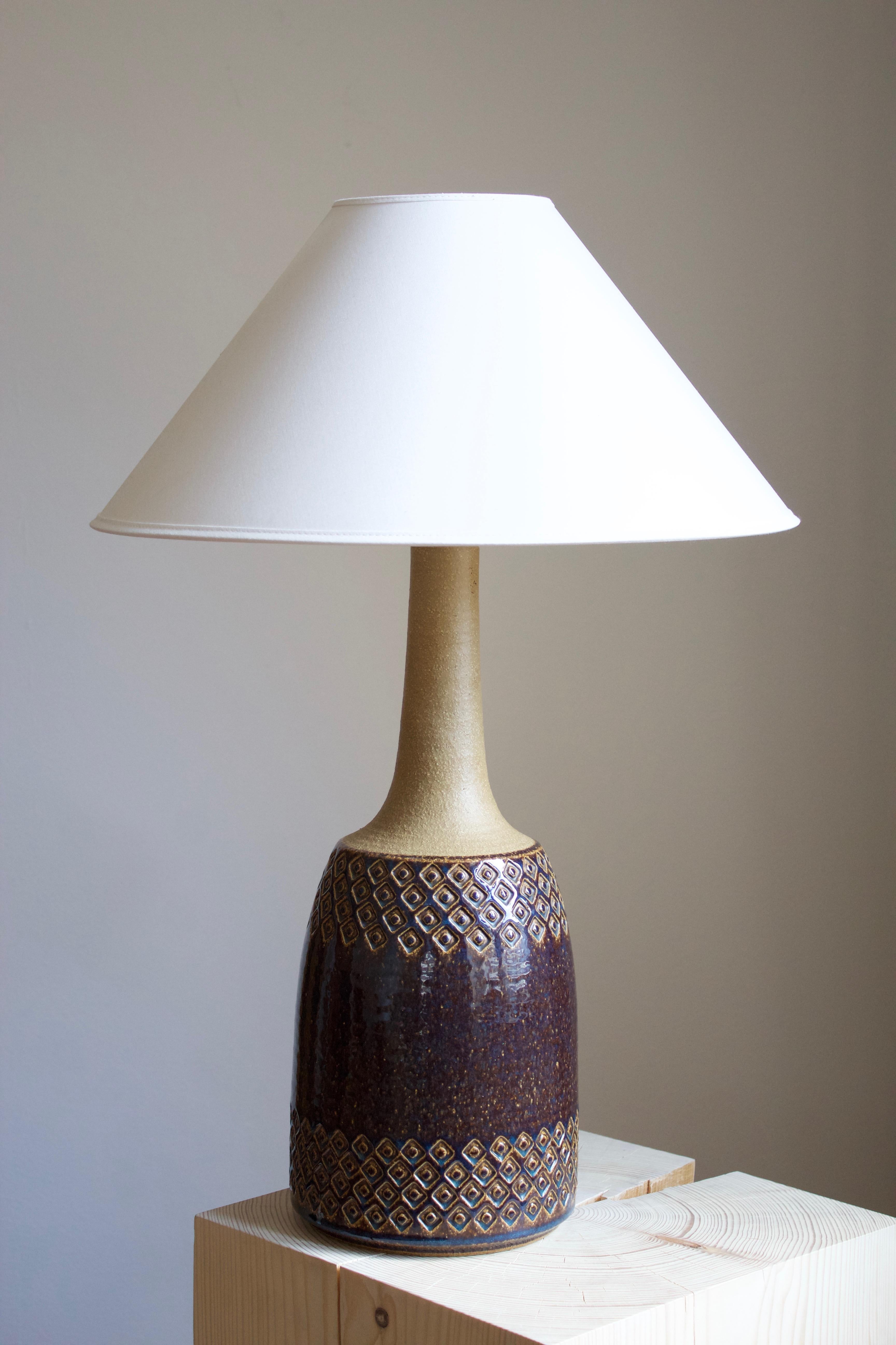 A large table lamp produced by Søholm Keramik, located on the island of Bornholm in Denmark. Features a highly artistic glazed and incised decor. 

Sold without lampshade. Stated dimensions exclude the lampshade. Height includes socket

Glaze
