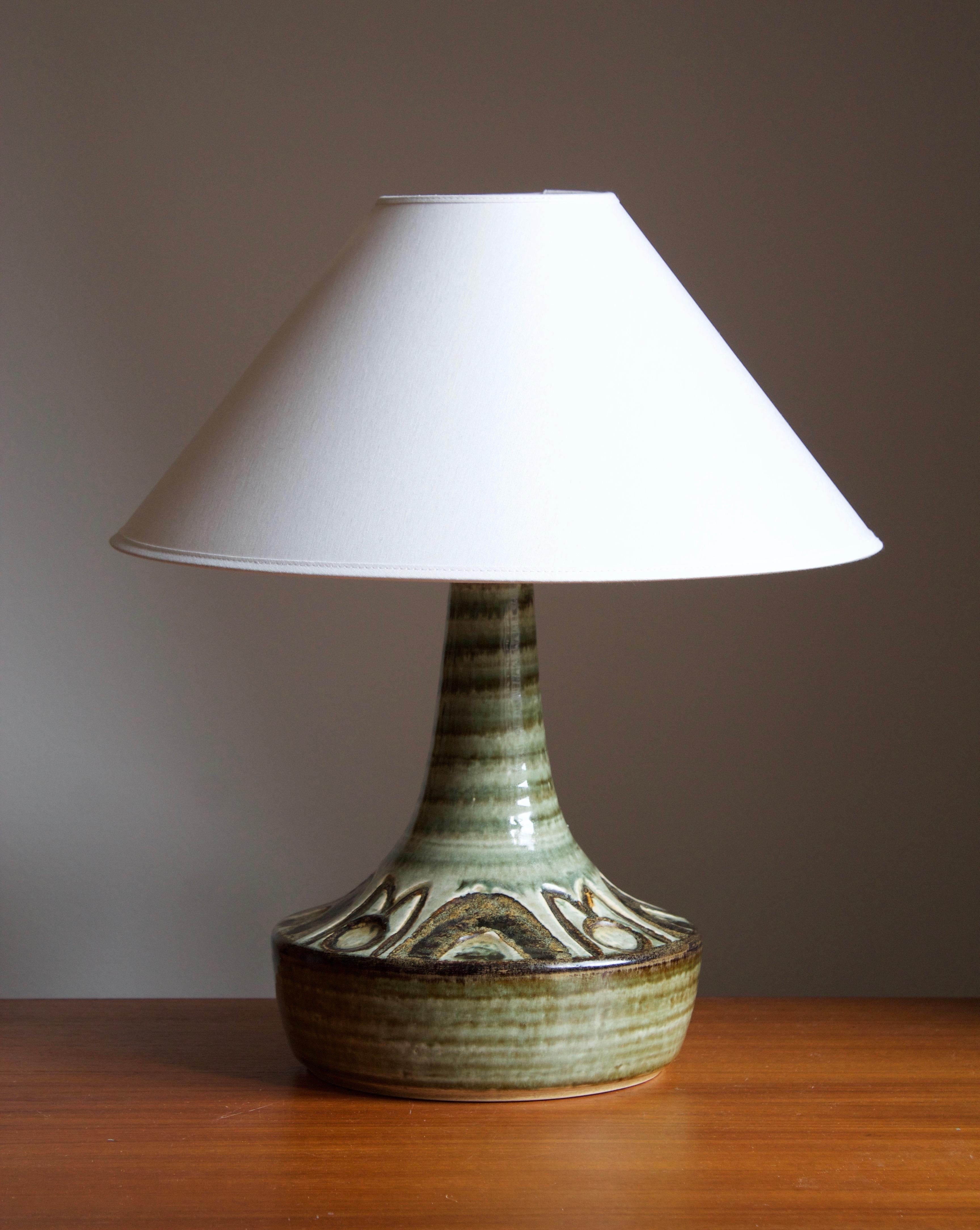 A table lamp produced by Søholm Keramik, located on the island of Bornholm in Denmark. Features a highly artistic glazed and incised decor.

Sold without lampshade. Stated dimensions exclude the lampshade.

Glaze features brown-green colors.

Other