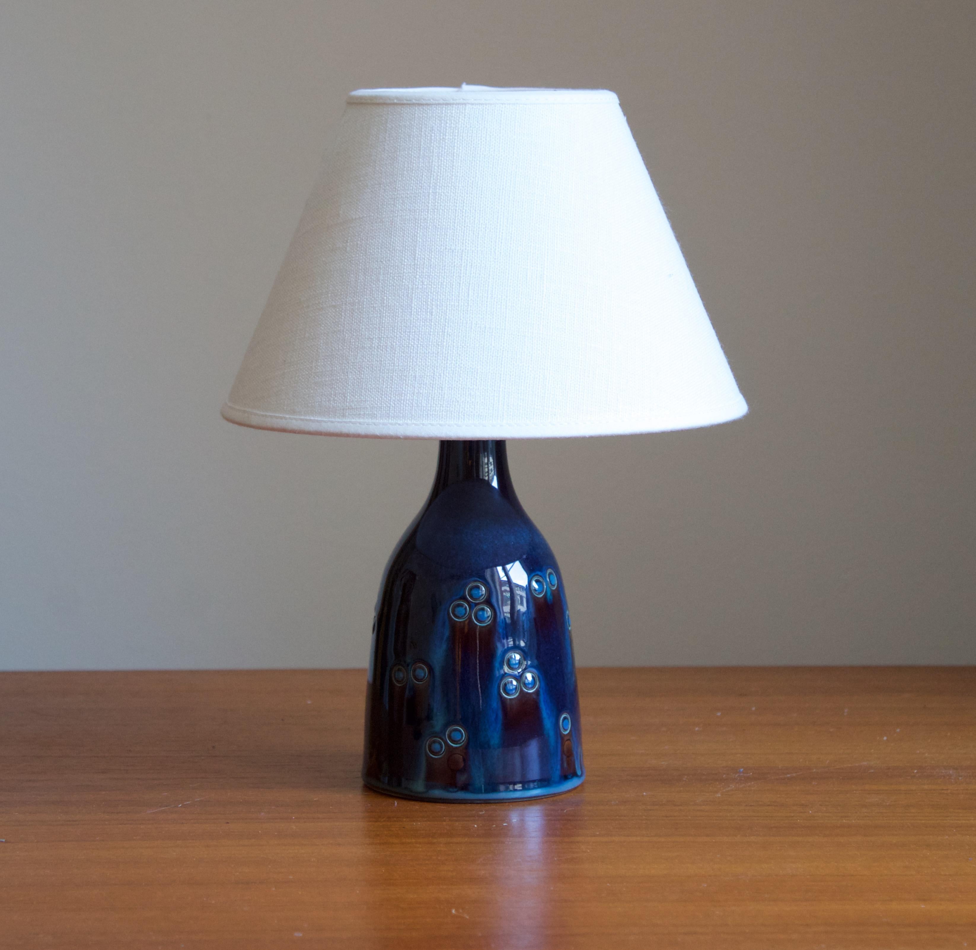 A small table lamp produced by Søholm Keramik, located on the island of Bornholm in Denmark. Features a highly artistic green / blue glaze.

Stated dimensions exclude lampshade. Height includes socket. Sold without lampshade.

Glaze features a blue