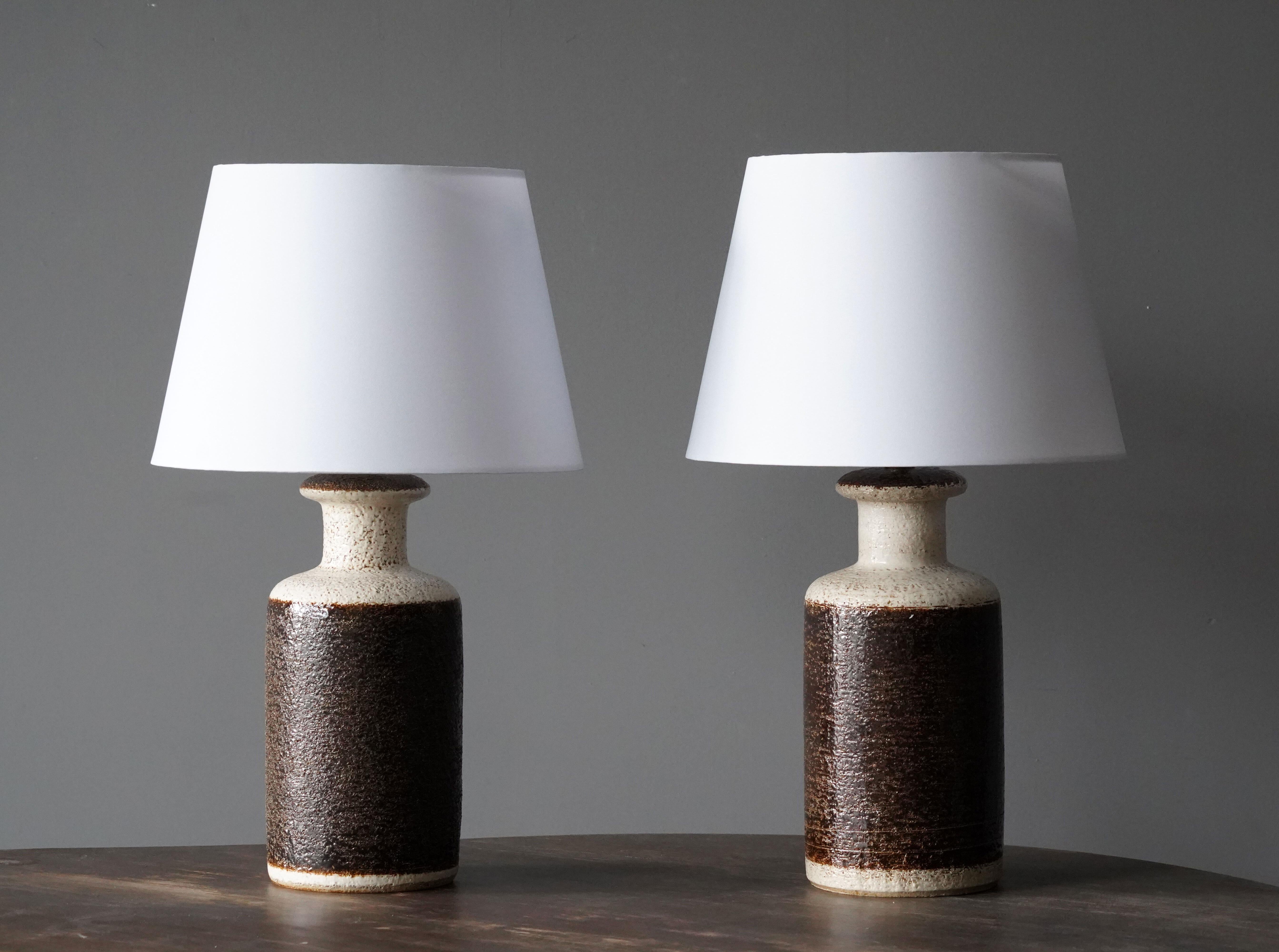 A pair of table lamps produced by Søholm Keramik, located on the island of Bornholm in Denmark. In a highly artistic brown / beige rake-style glaze. The lamps are not identical, adding to the rustic expression of the pair. 

Lampshades are