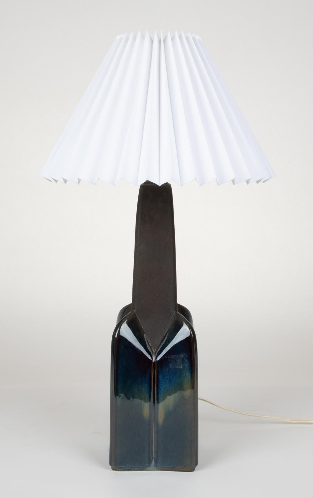 A striking Danish mid-century table lamp in ceramic with a metallic blue glaze, manufactured by Soholm Stentoj. This geometric faceted design with a sleek tapered top is attributed to Einar Johansen, who partnered with Soholm to create Scandinavian