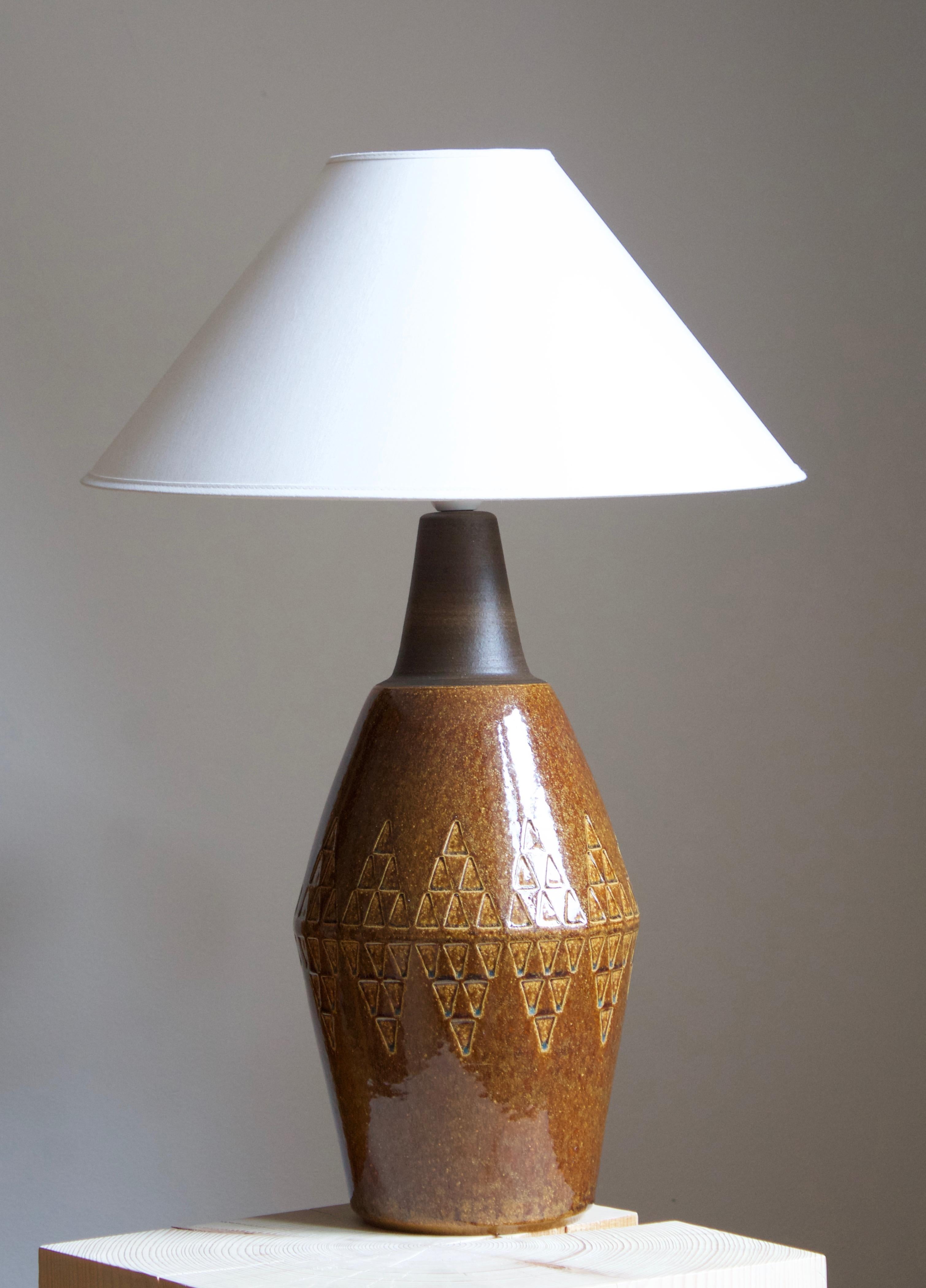 A large table lamp produced by Søholm Keramik, located on the island of Bornholm in Denmark. Features a highly artistic glazed decor. 

Sold without lampshade. Stated dimensions exclude the lampshade.

Glaze features a brown color.

Other designers