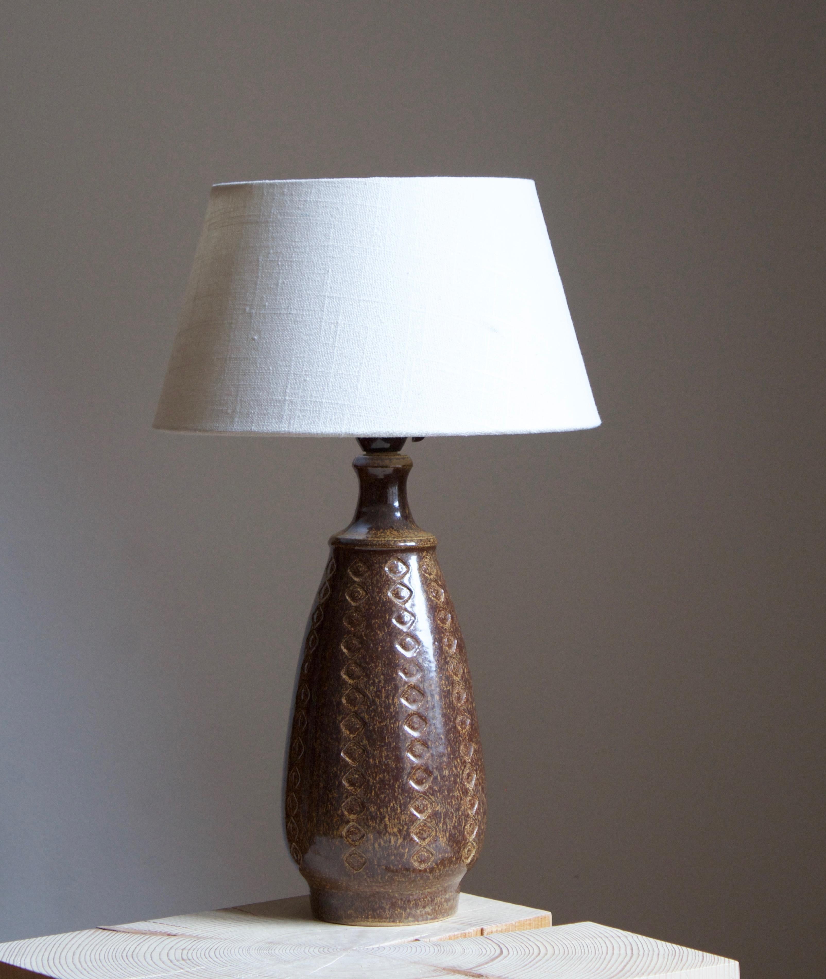 A large table lamp produced by Søholm Keramik, located on the island of Bornholm in Denmark. Features a highly artistic glazed and incised decor. 

Sold without lampshade. Stated dimensions exclude the lampshade.

Glaze features a brown