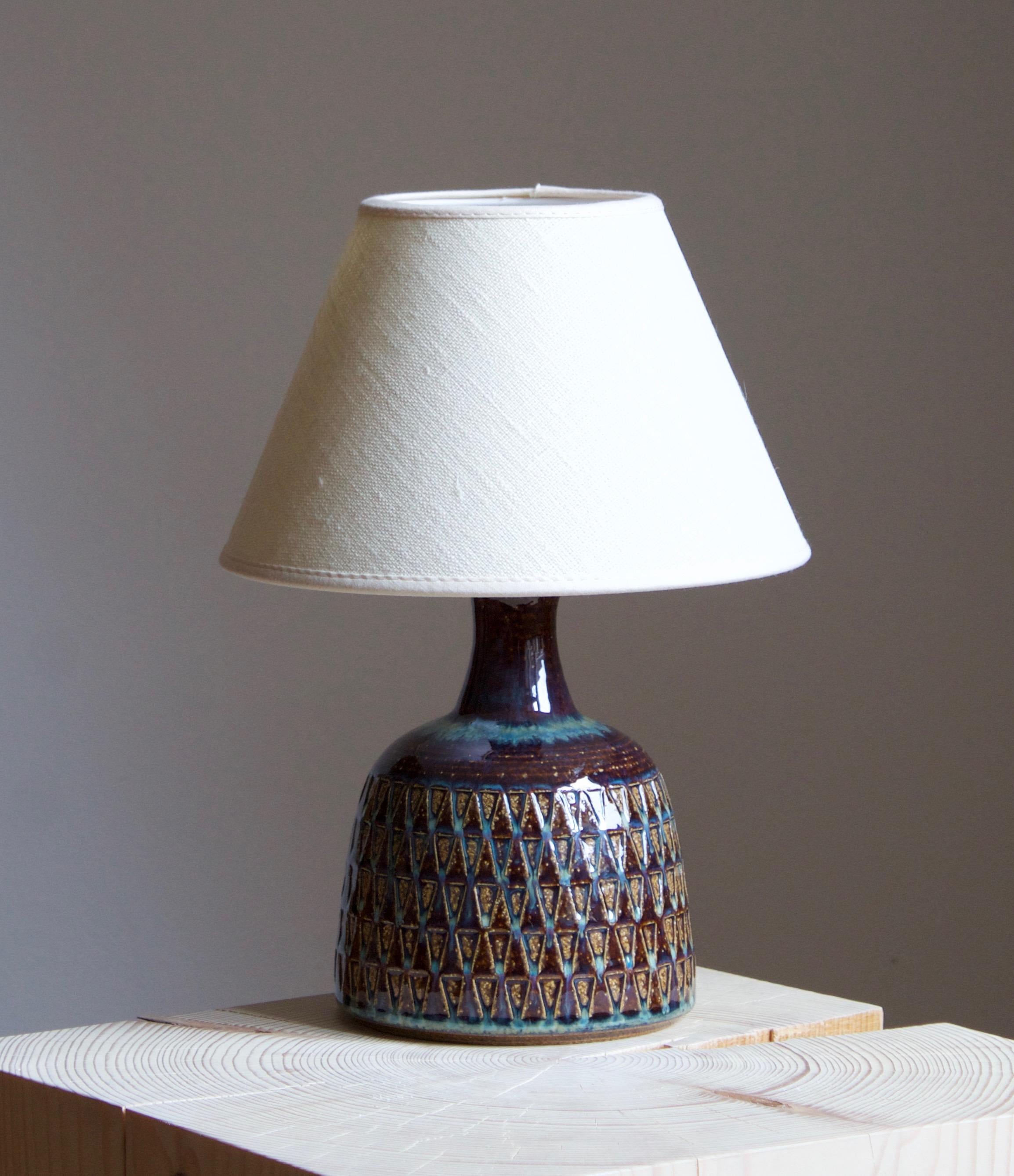 A large table lamp produced by Søholm Keramik, located on the island of Bornholm in Denmark. Features a highly artistic glazed and incised decor. 

Sold without lampshade. Stated dimensions exclude the lampshade.

Glaze features blue-brown