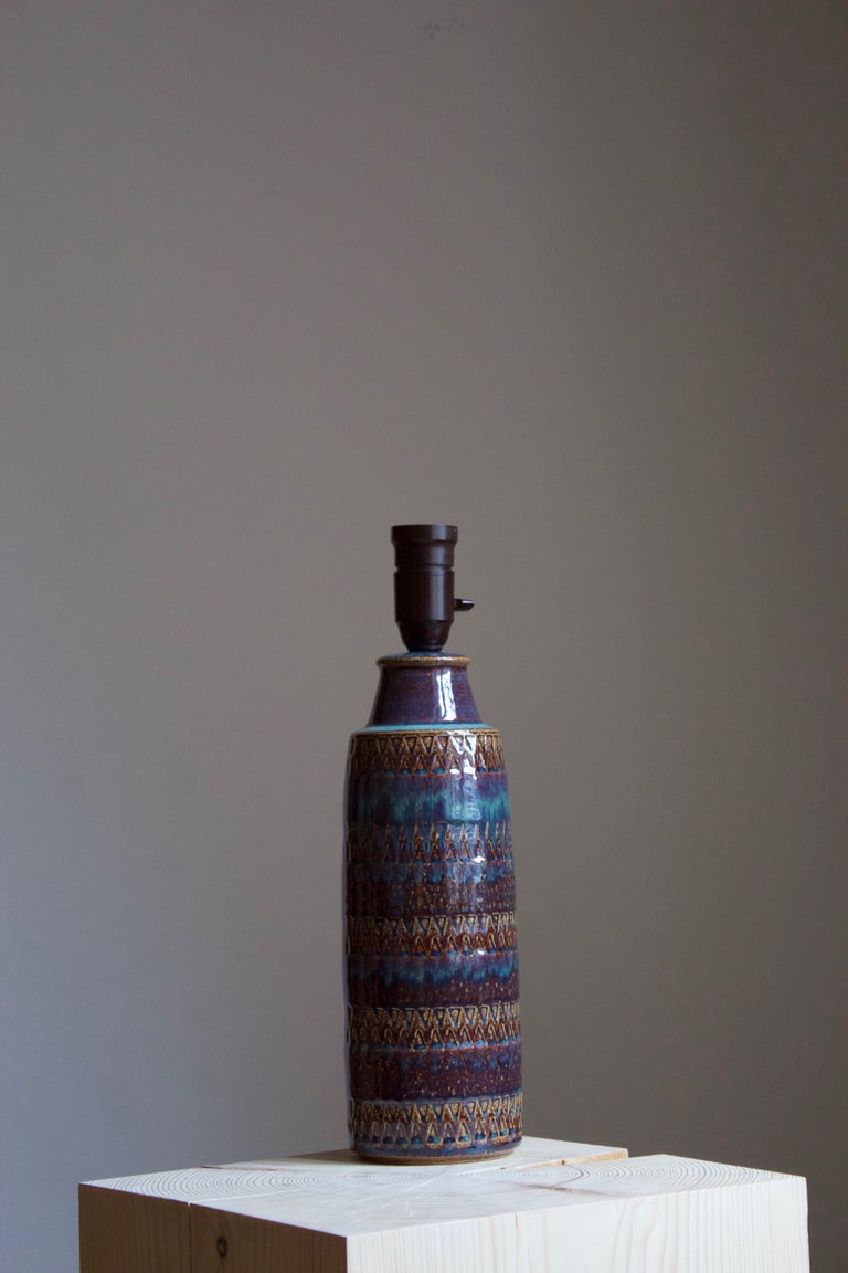 A table lamp produced by Søholm Keramik, located on the island of Bornholm in Denmark. Features a highly artistic glazed and incised decor. 

Sold without lampshade. Stated dimensions exclude the lampshade.

Glaze features blue-brown-red