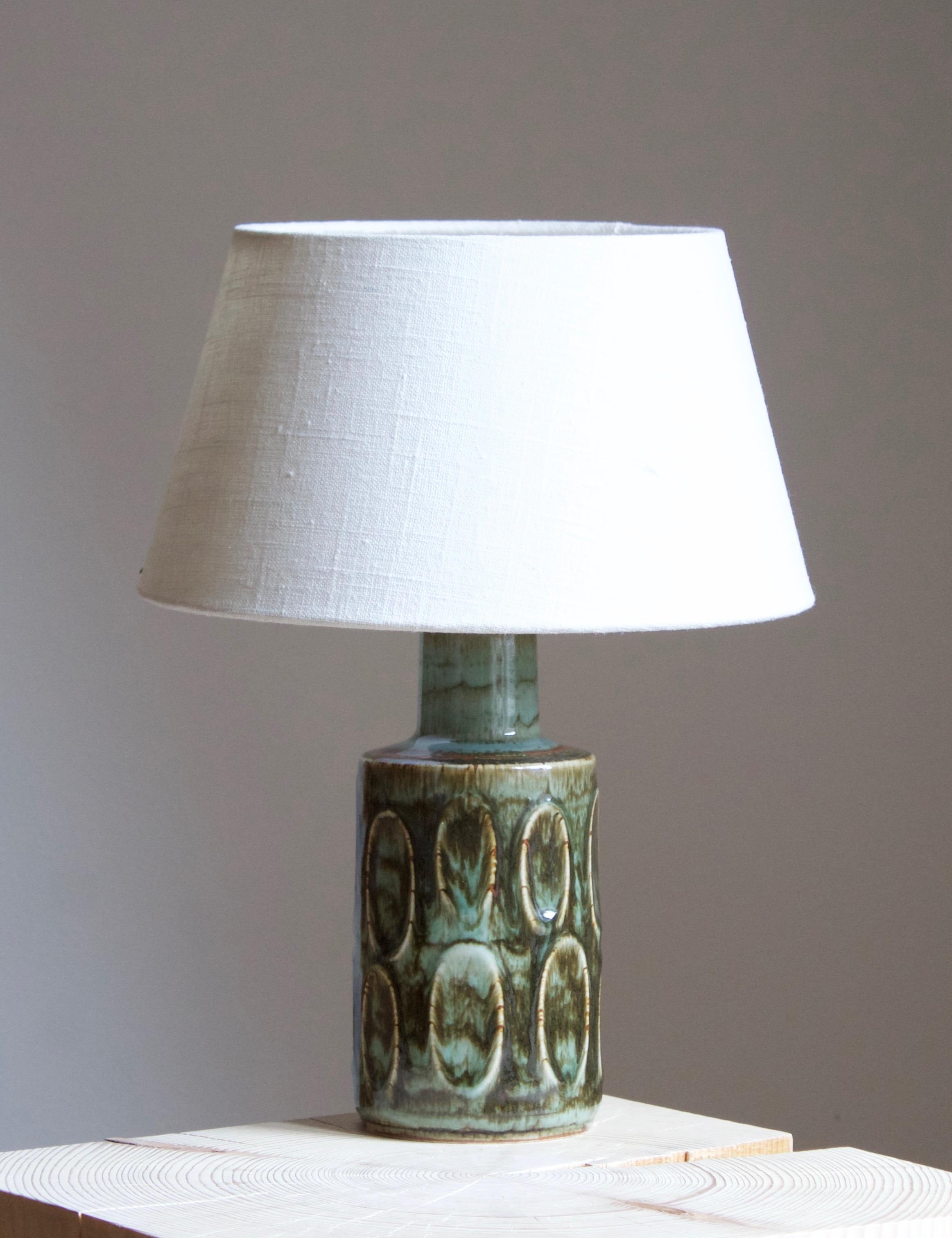 A table lamp produced by Søholm Keramik, located on the island of Bornholm in Denmark. Features a highly artistic glazed and incised decor. 

Sold without lampshade. Stated dimensions exclude the lampshade. Height includes socket.

Glaze features