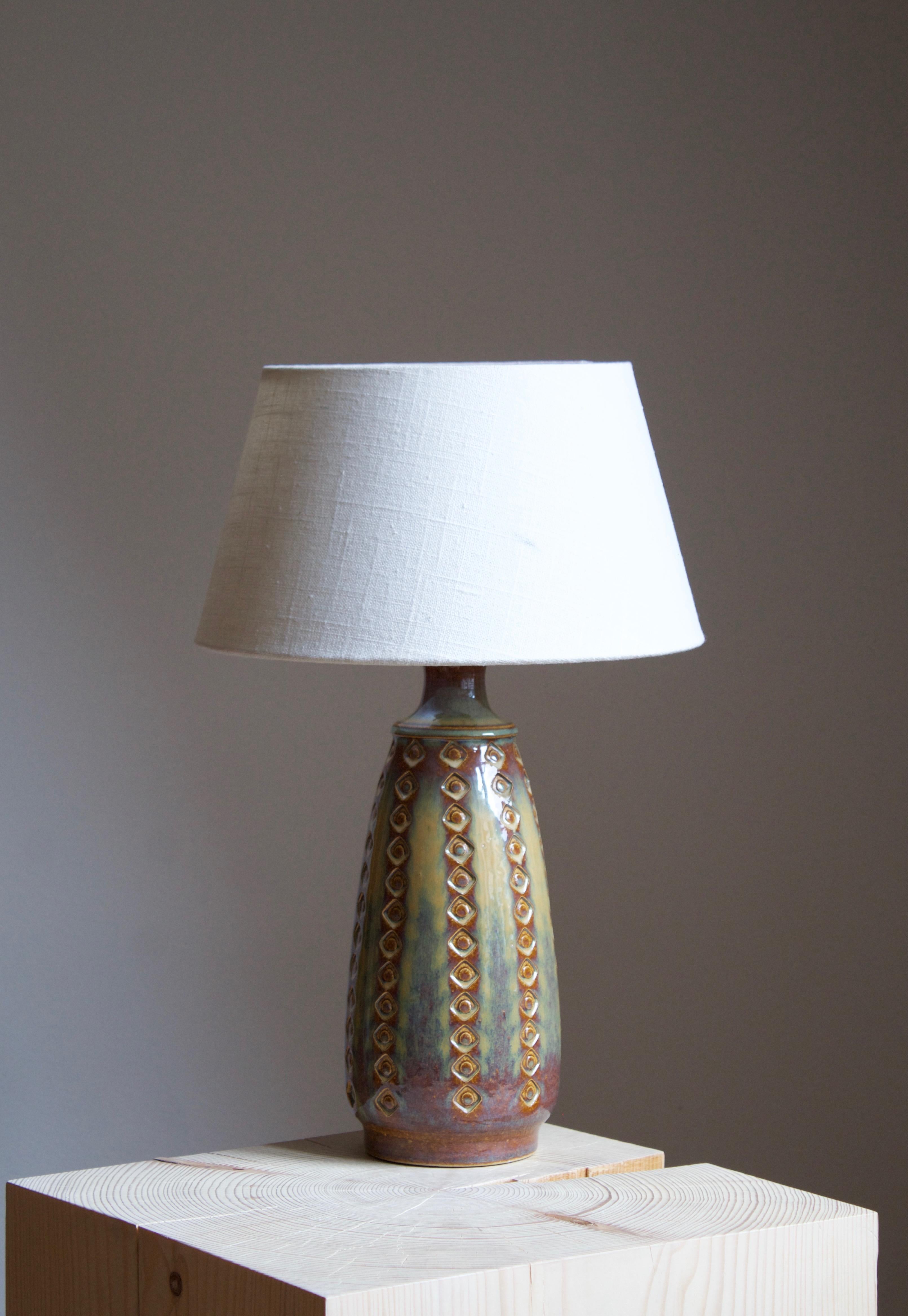 A large table lamp produced by Søholm Keramik, located on the island of Bornholm in Denmark. Features a highly artistic glazed and incised decor. 

Sold without lampshade. Stated dimensions exclude the lampshade.

Glaze features green-brown